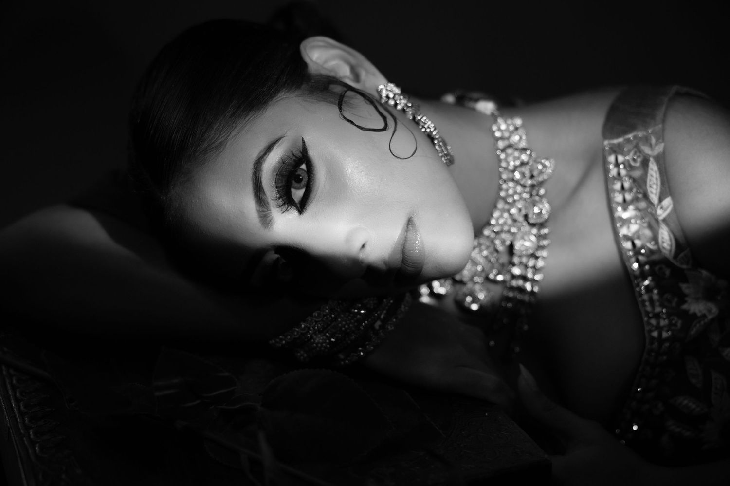 Glamorous South Asian bride in black and white portrait wearing ornate jewelry and dramatic eye makeup.