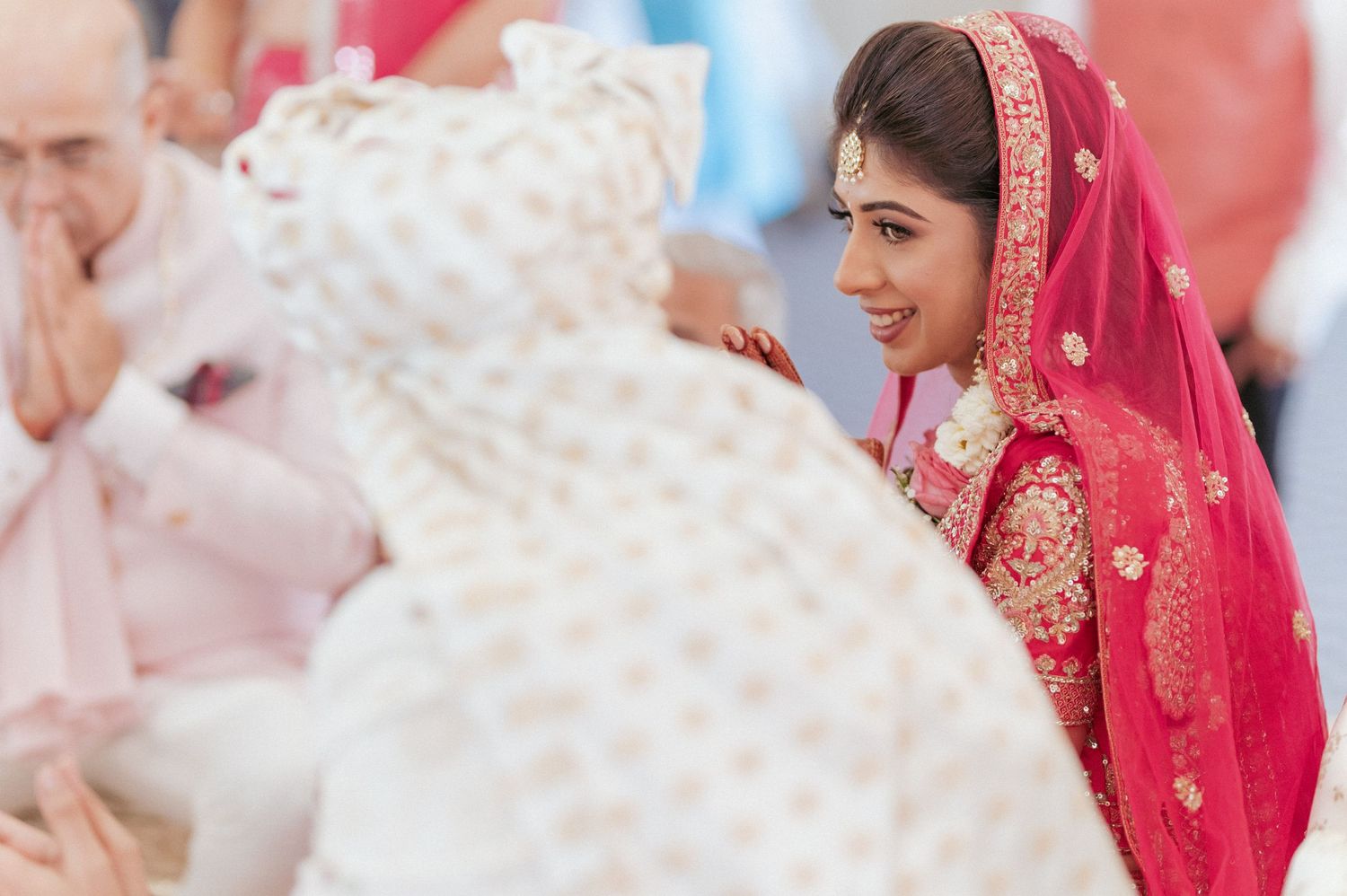 Beautiful Indian bride in red bridal lehenga smiling during traditional Hindu wedding.