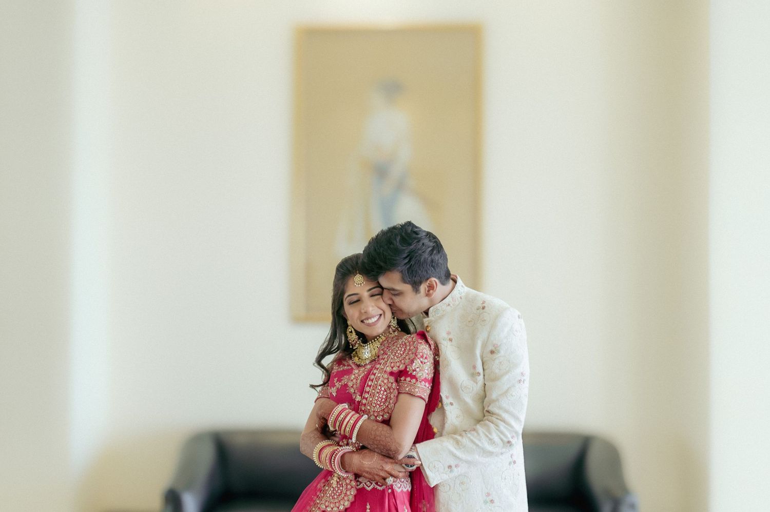 Indian bride and groom share a tender embrace in a softly lit wedding portrait.