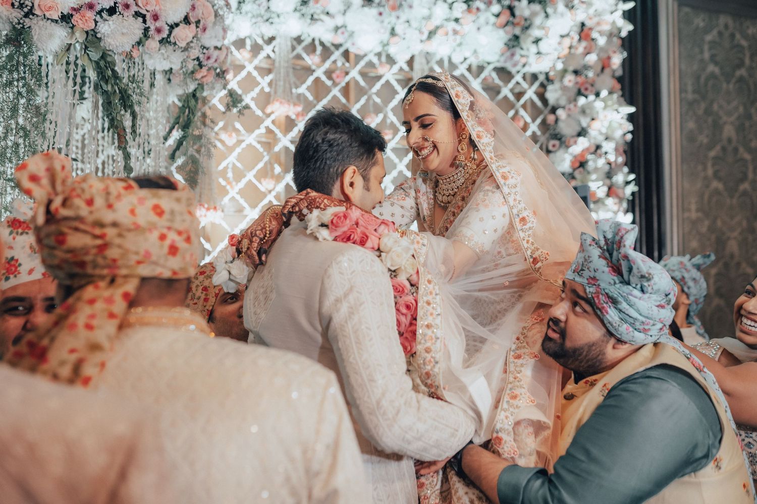 Indian bride and groom sharing a joyful moment during traditional garland exchange at wedding ceremony.