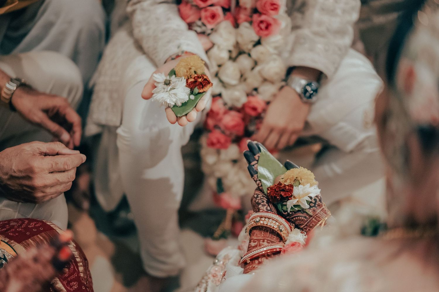 Close-up of Indian wedding ceremony hands exchanging floral offerings in traditional South Asian bridal ritual.