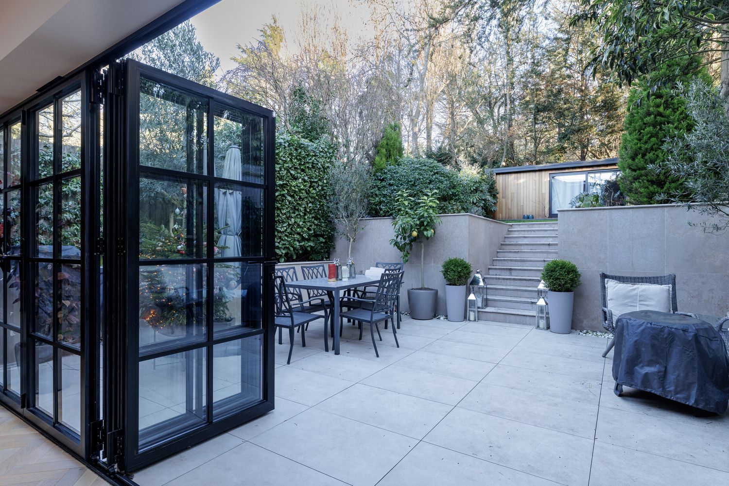 Steel-framed glazed doors opening onto a paved garden terrace