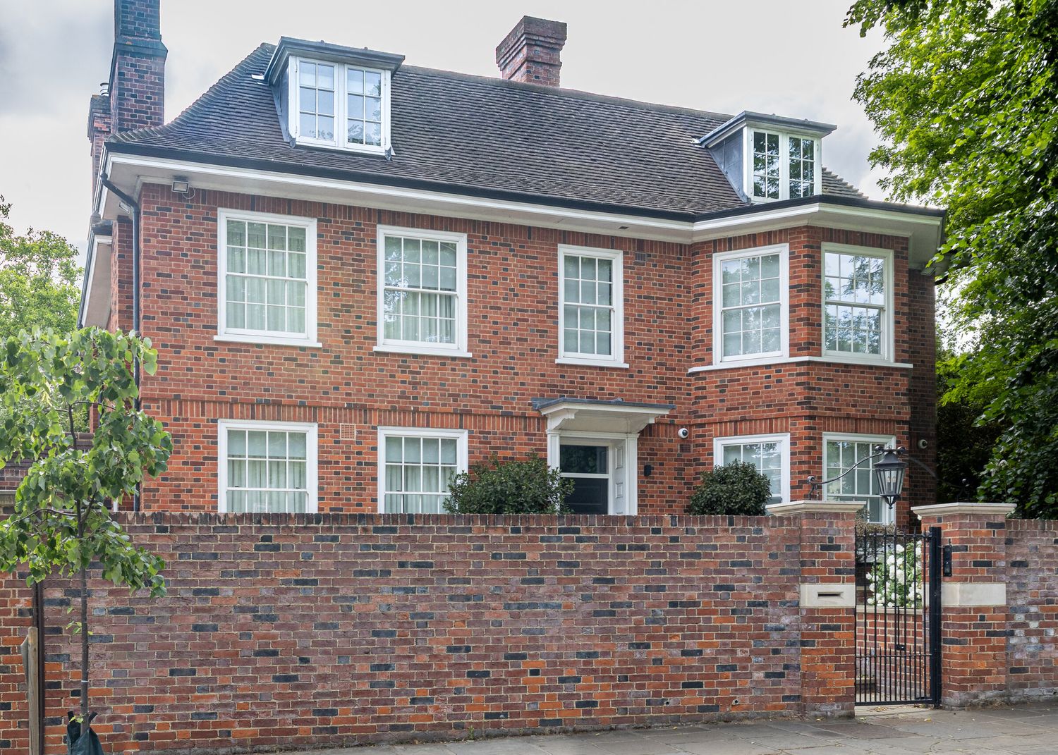 Red-brick detached house behind a garden wall, London