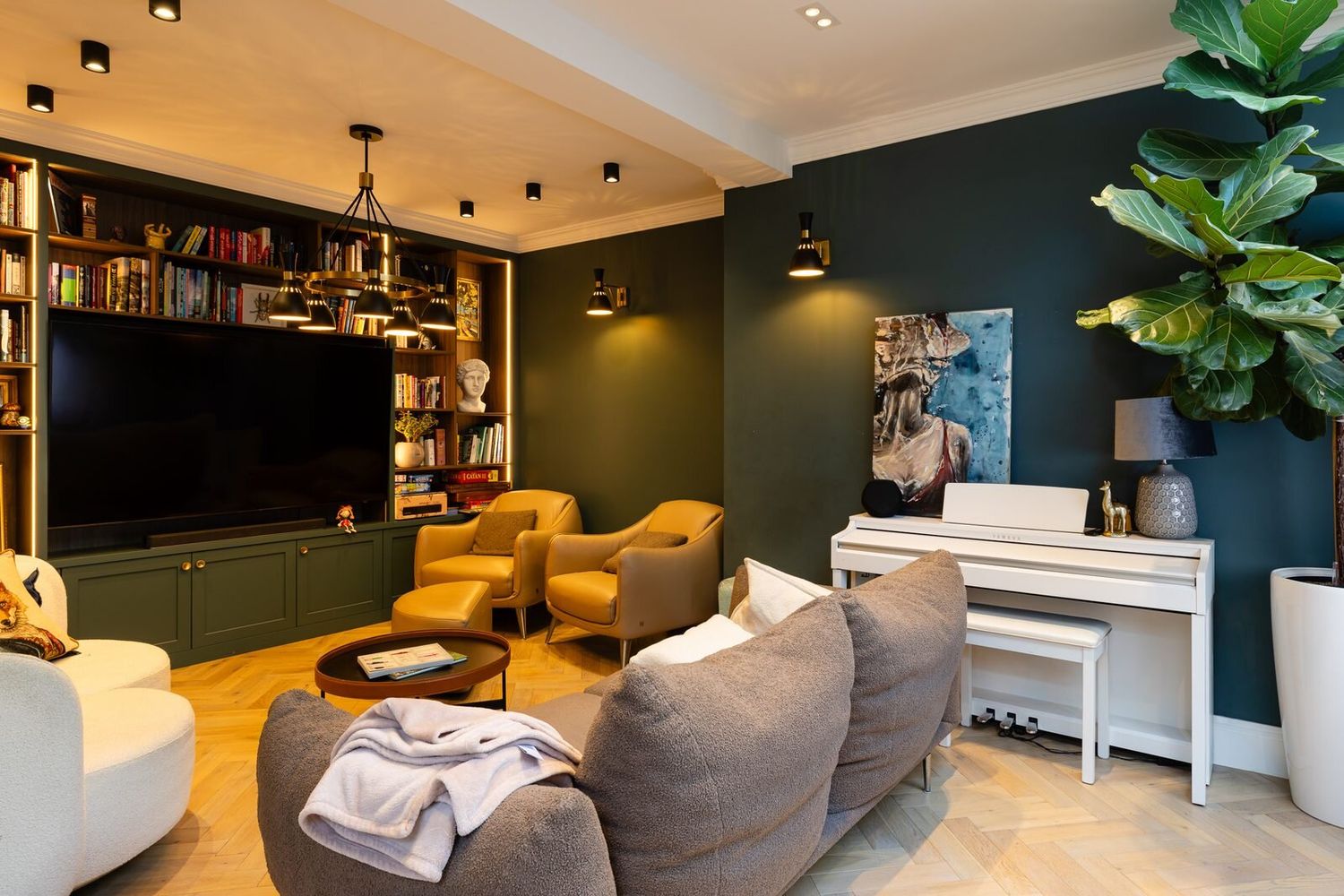 Media room with dark green walls, built-in bookshelves and warm lighting