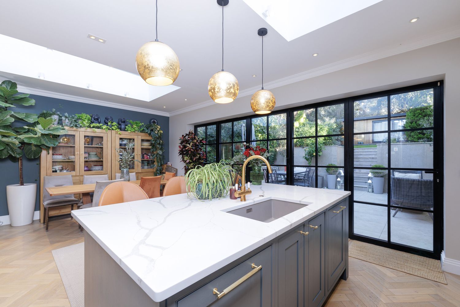 Kitchen extension with marble island, brass pendant lights and steel-framed glazing