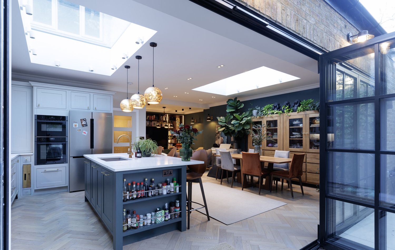 Open-plan kitchen and dining space with rooflight and folding glazed doors