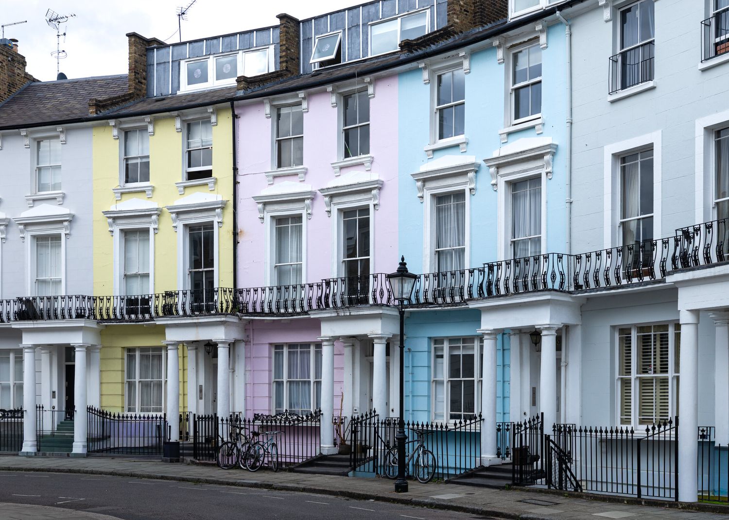 Row of pastel-coloured Victorian terraced houses with iron balconies, London