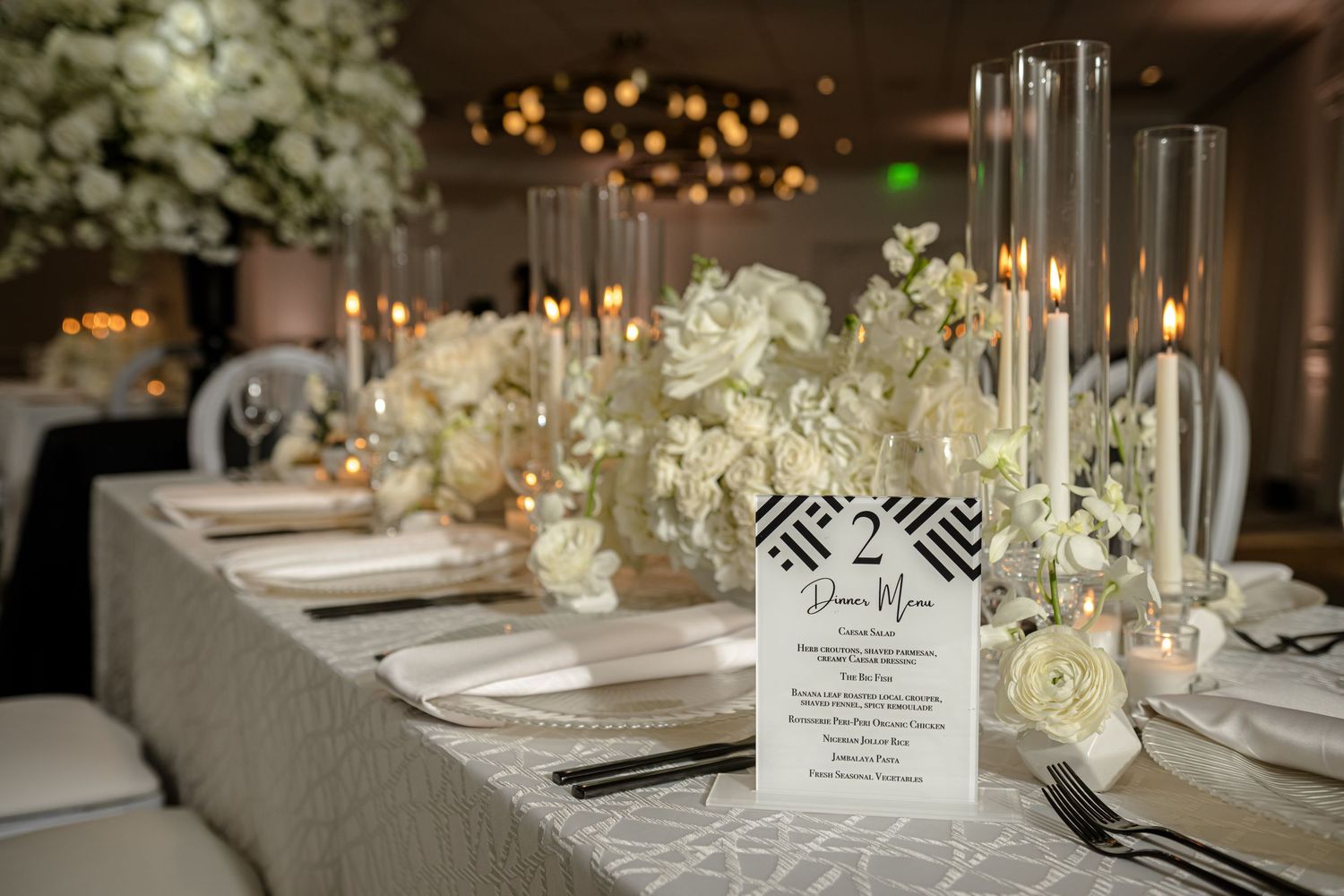 Elegant wedding reception tables decorated with white floral centerpieces and glowing candlelight create a romantic atmosphere.