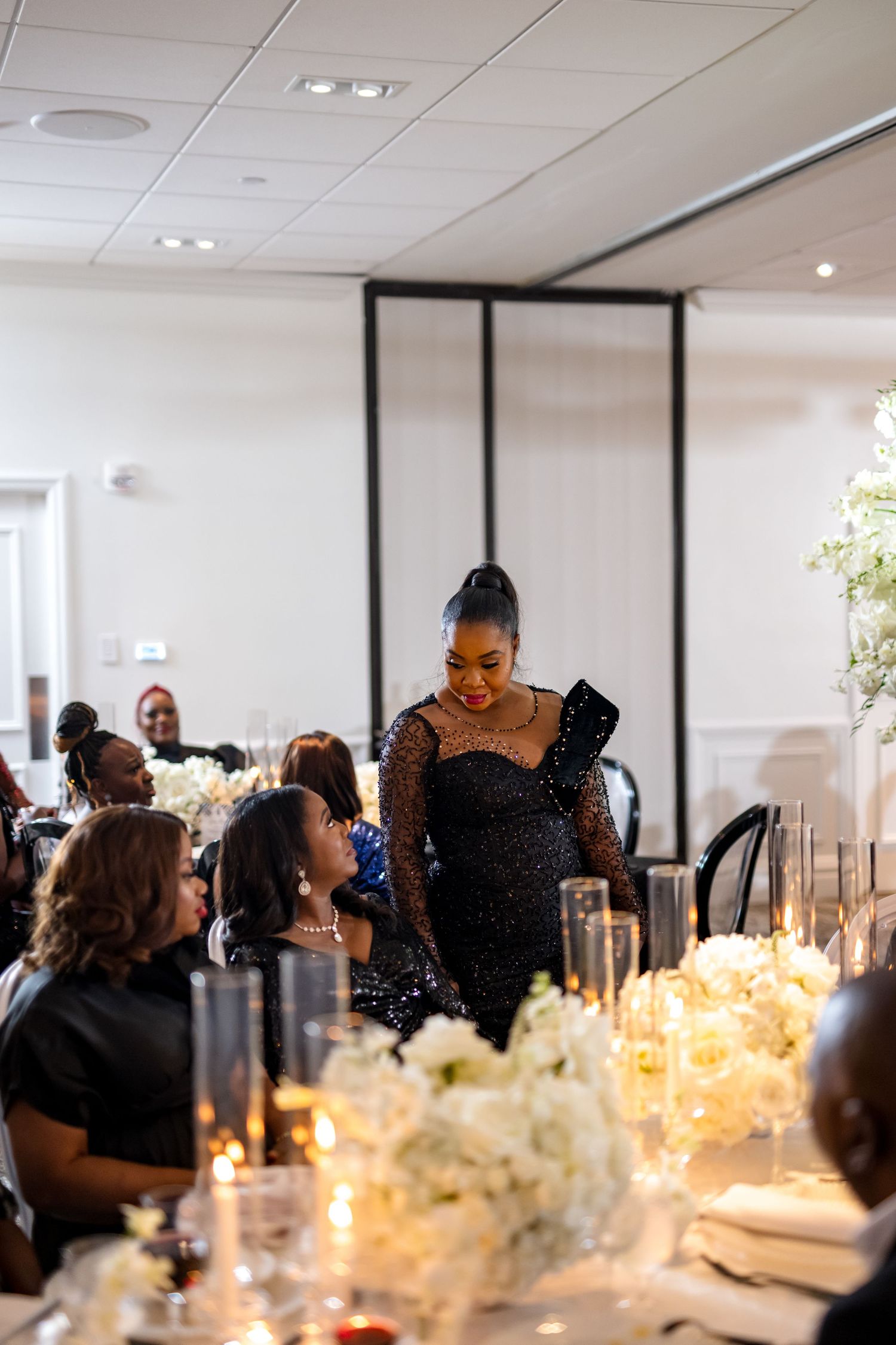 People gathered around an elegant dining table with floral centerpieces in a modern event space.
