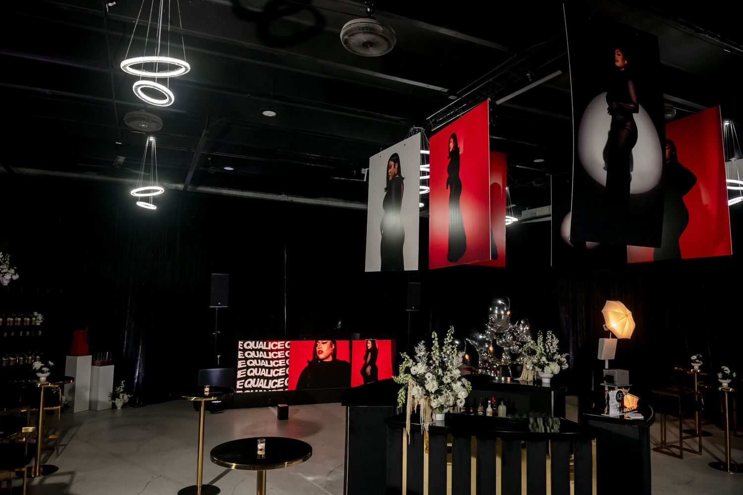 Dark gym interior with black walls and red accents features workout equipment and training areas.