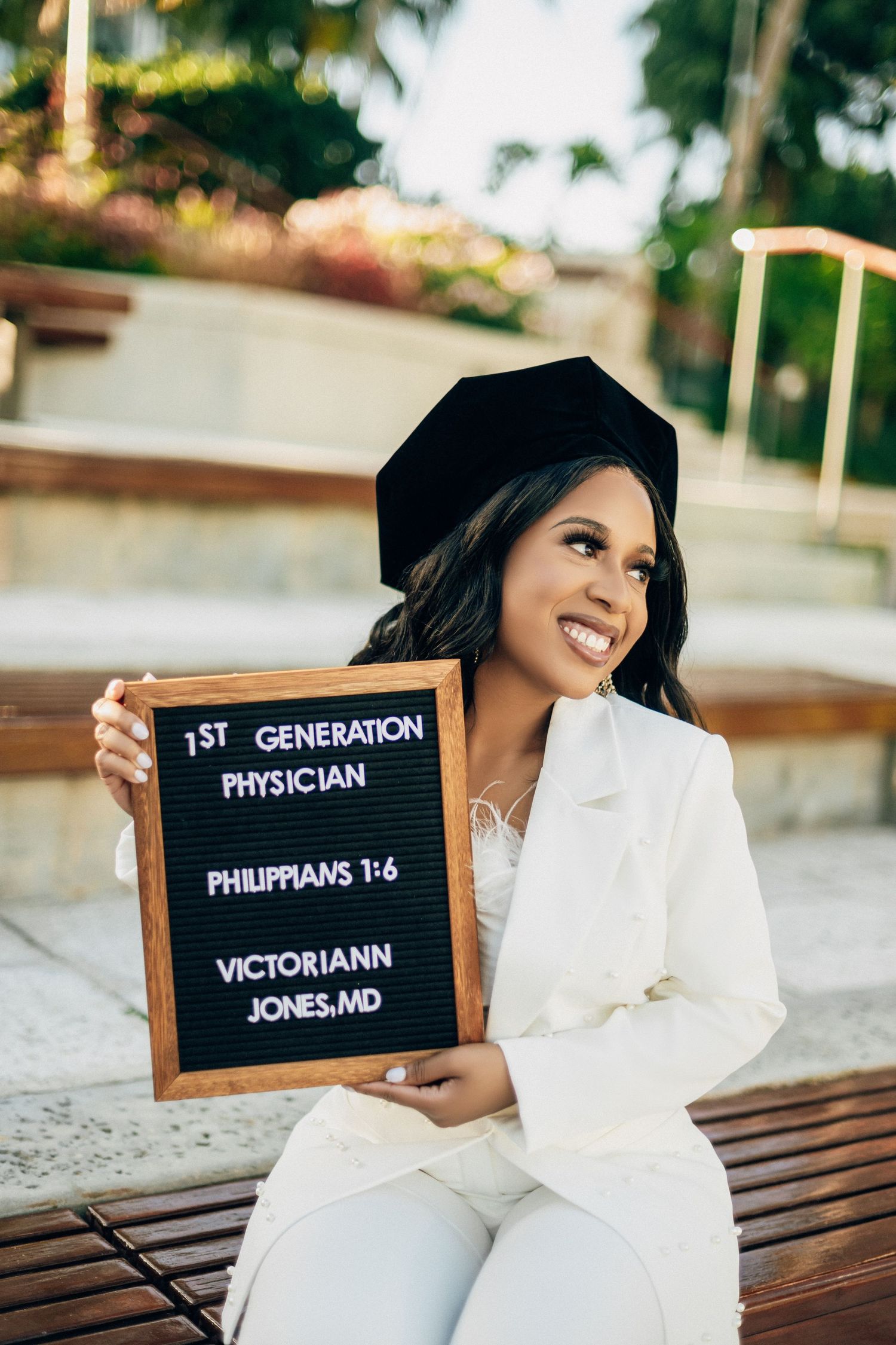 A series of graduation photos showing a person in white holding letter boards with different text messages on a bench.