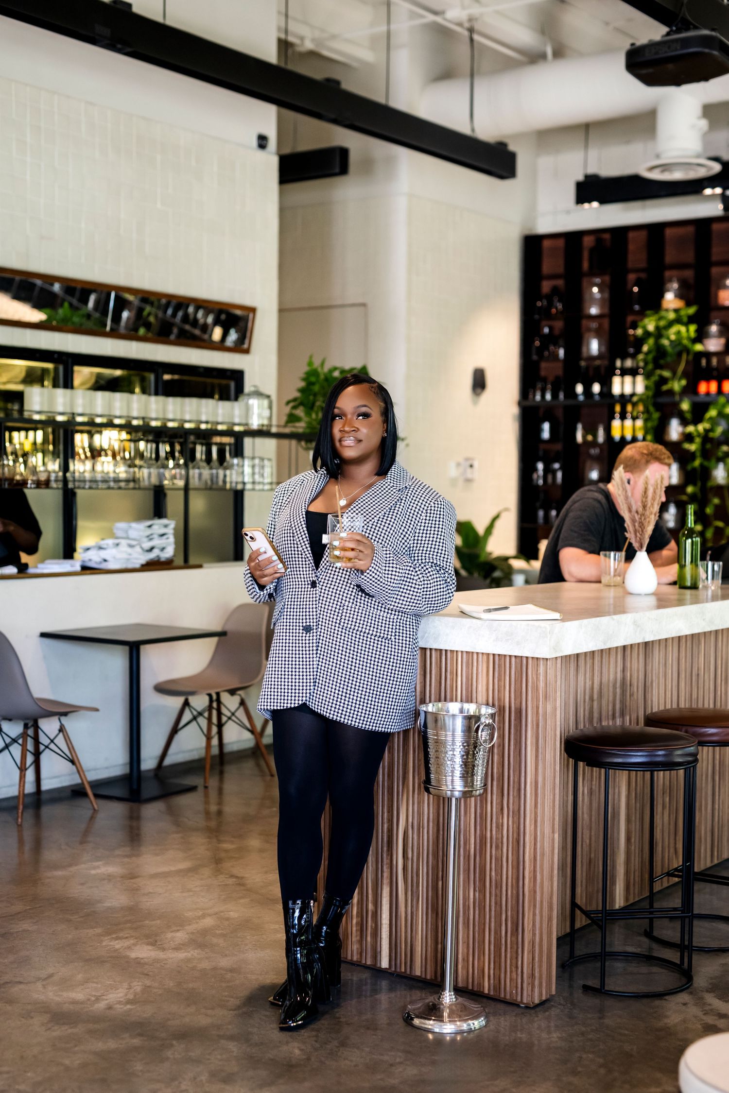 Woman enjoying drinks at modern industrial-style bar with wooden countertops.