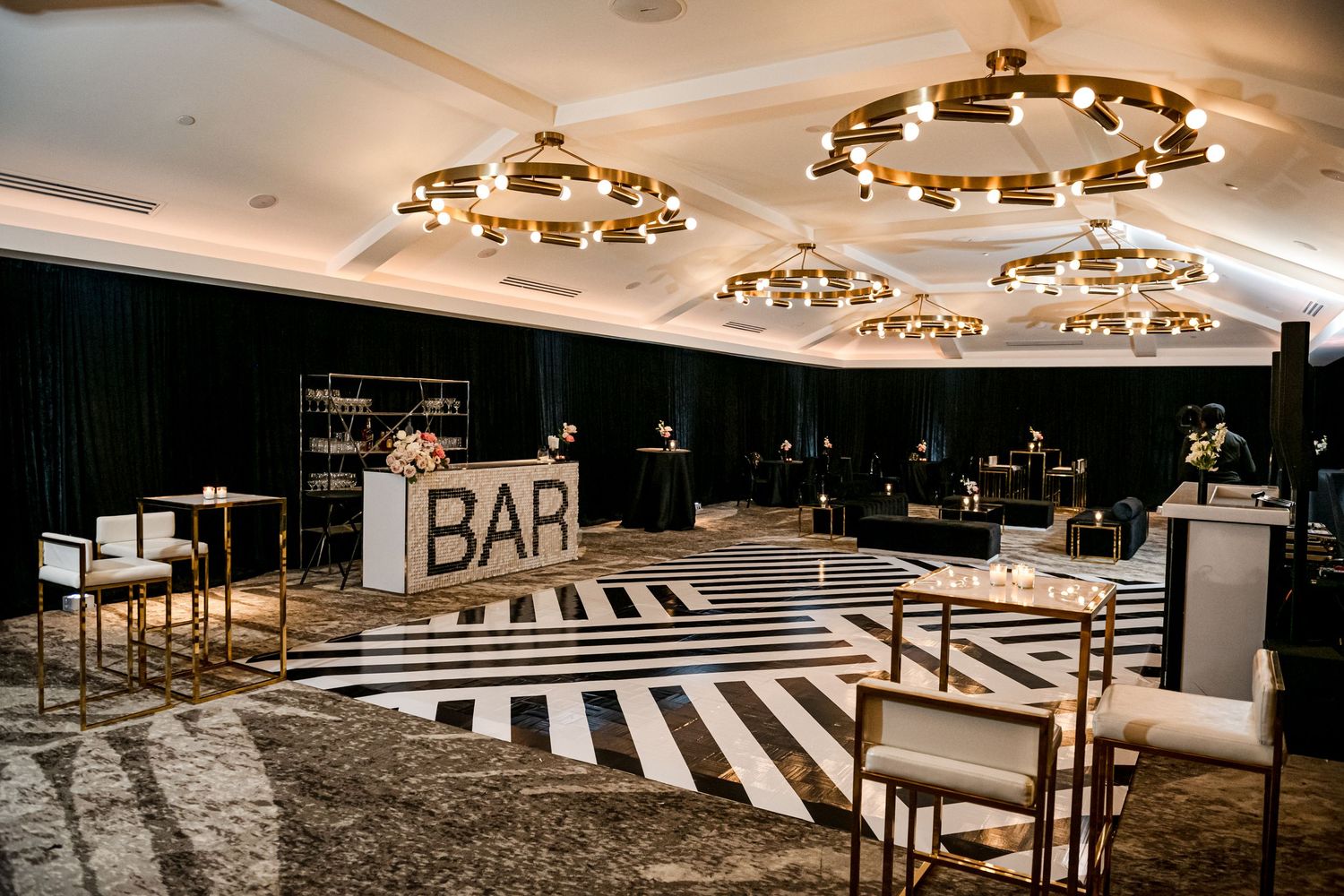 Modern bowling alley interior with black and white geometric lanes, ambient lighting, and sleek bar area in background.