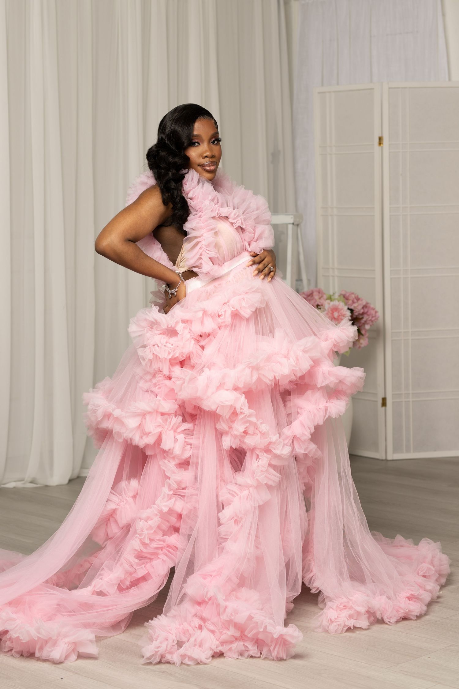 A flowing pink tulle gown with dramatic ruffles and volume is showcased in a series of glamorous poses.