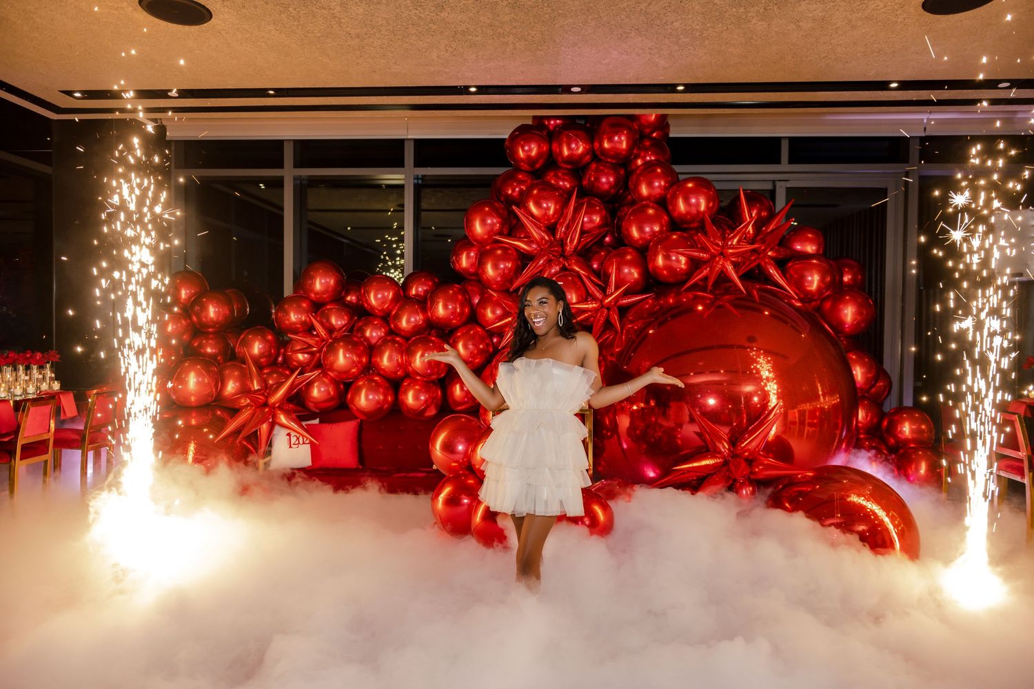 Elegant red balloon backdrop with sparklers creates dramatic atmosphere for glamorous photo session.
