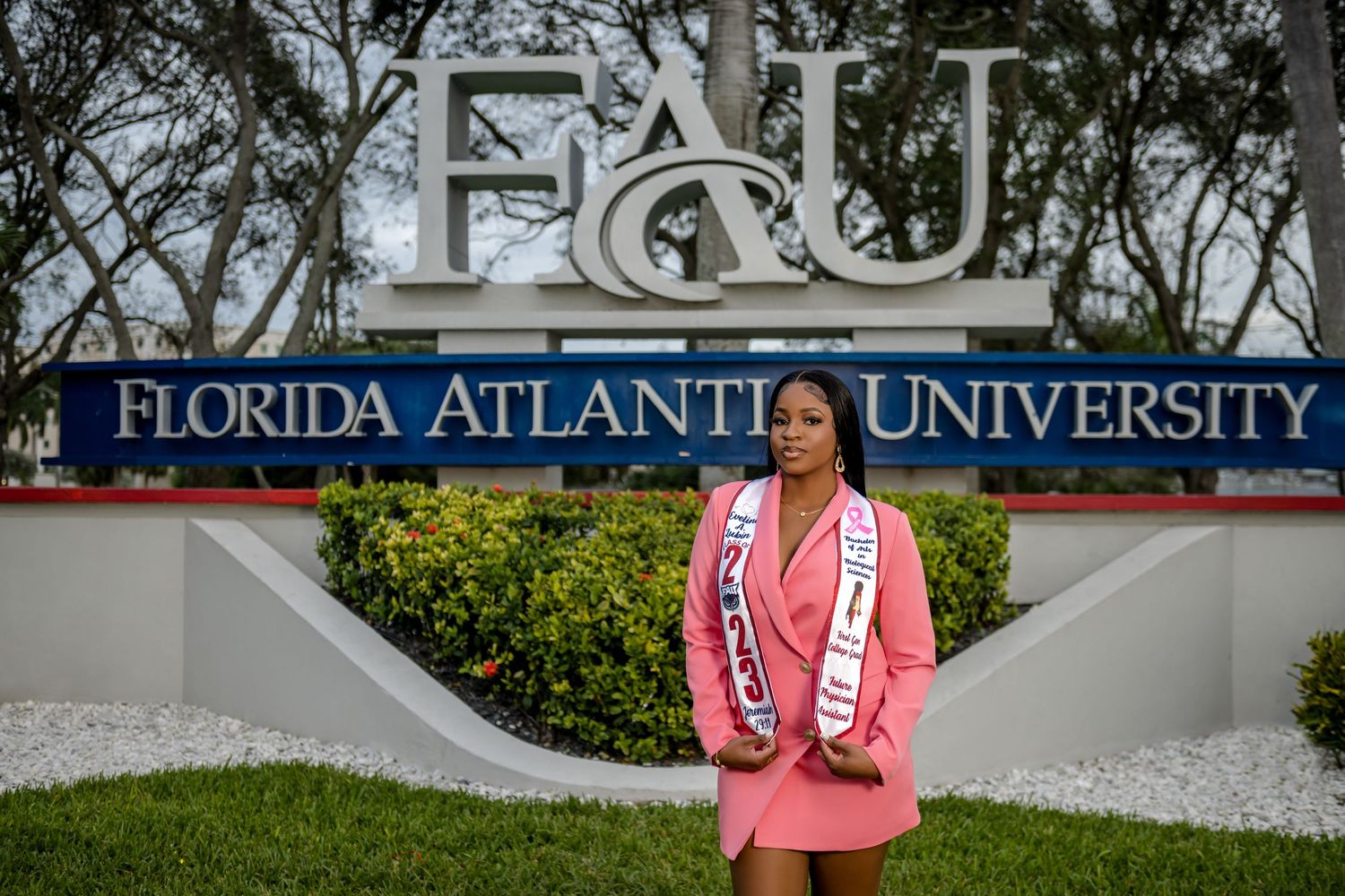 Students gather at Florida Atlantic University campus entrance with signage and palm trees visible in background.
