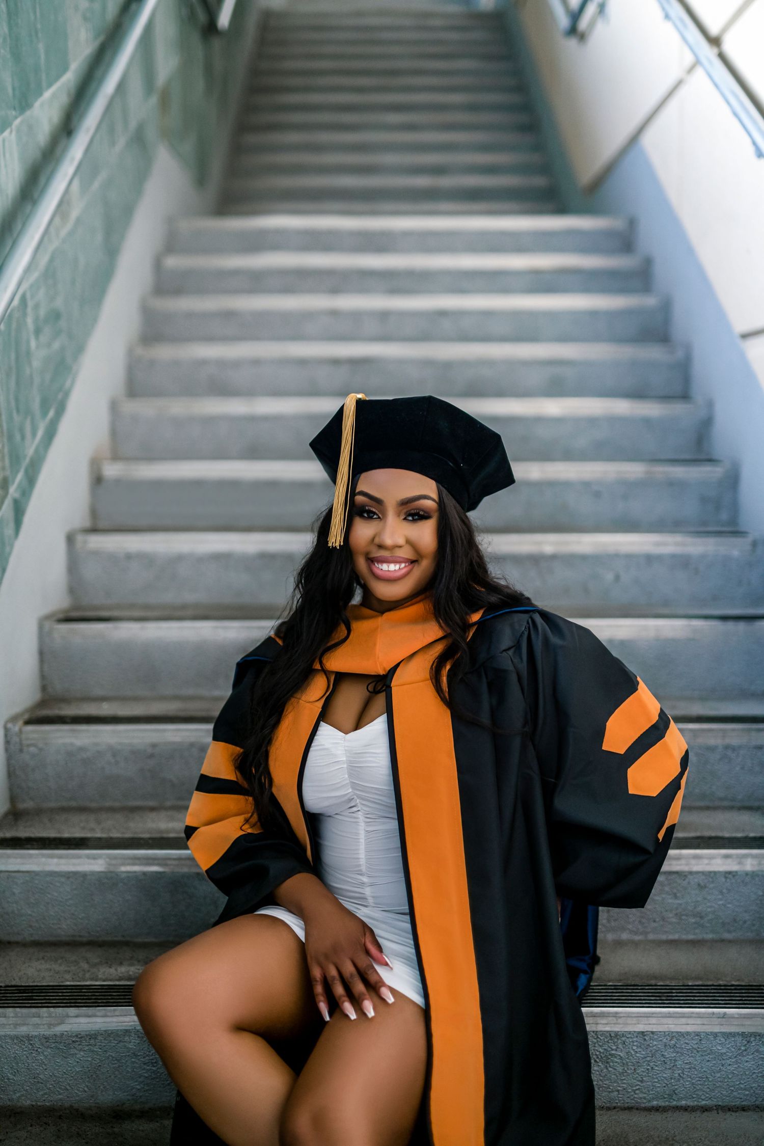 A graduation photoshoot series showing a person in black cap and gown with orange stole posing on concrete stairs.