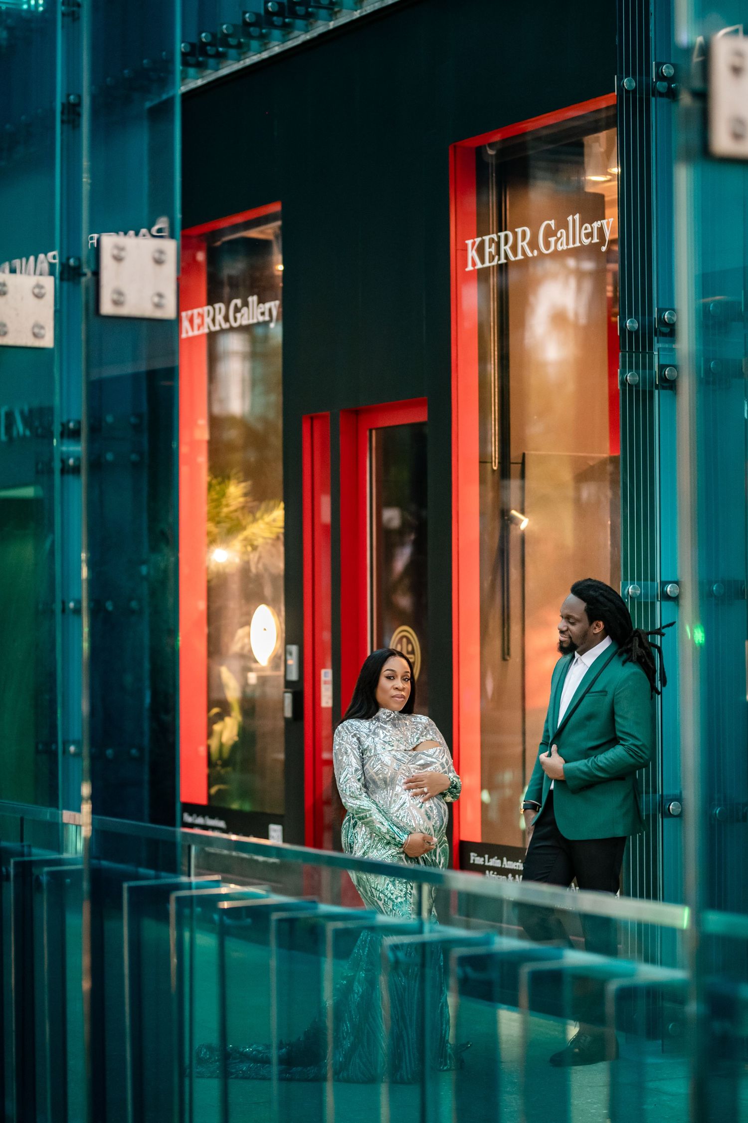 People having a conversation outside the Kerr Gallery with teal walls and red trim in an urban setting.