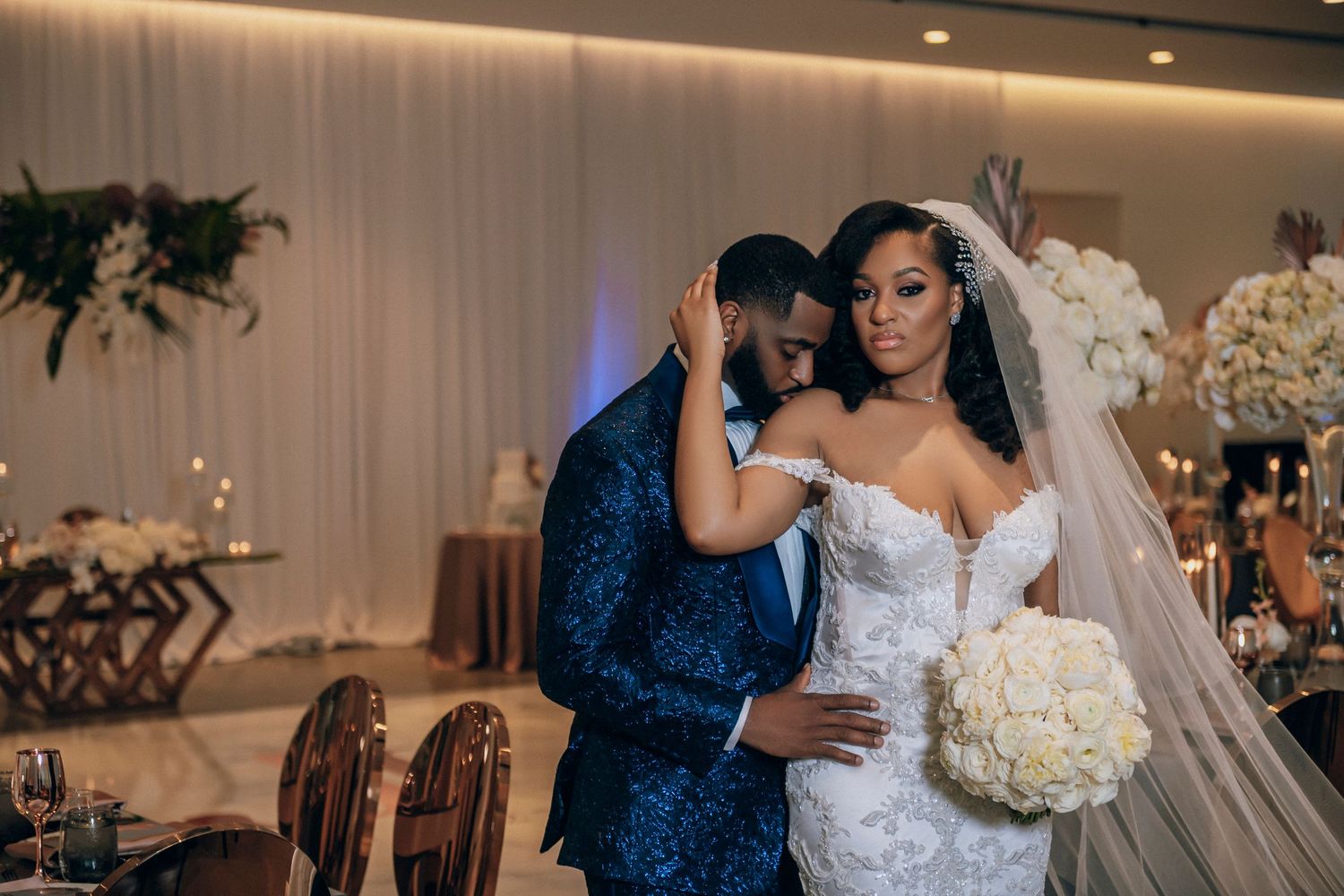 Elegant indoor wedding portrait featuring luxurious white florals and romantic lighting.