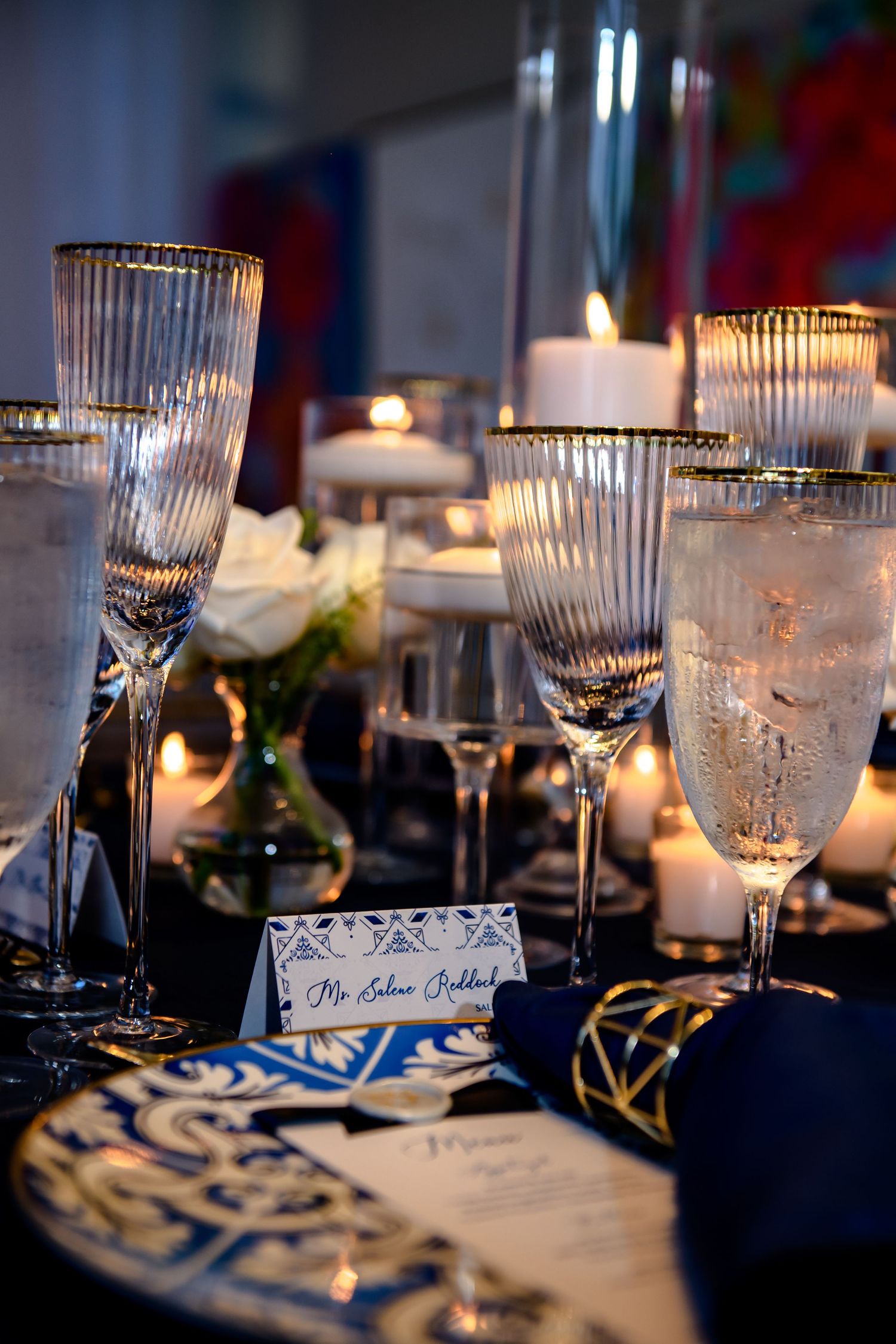 Elegant wedding table setting with crystal glasses, candlelight and blue accents.