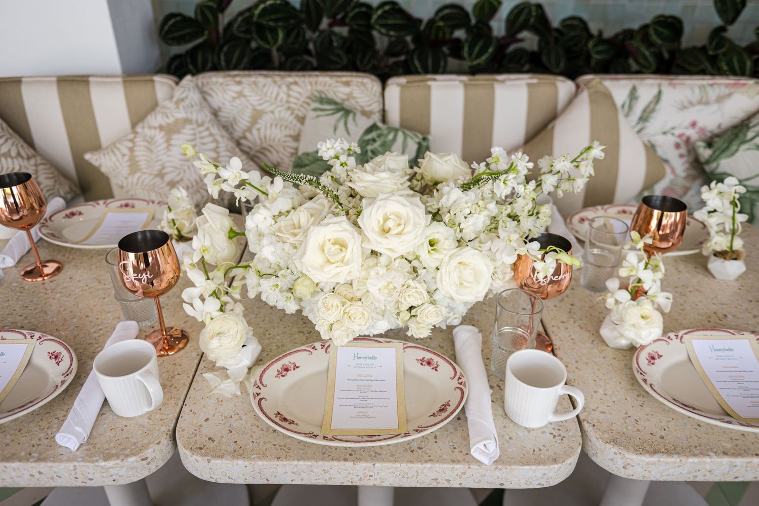 White and pink floral table centerpieces with roses and hydrangeas arranged on dining tables with place settings.