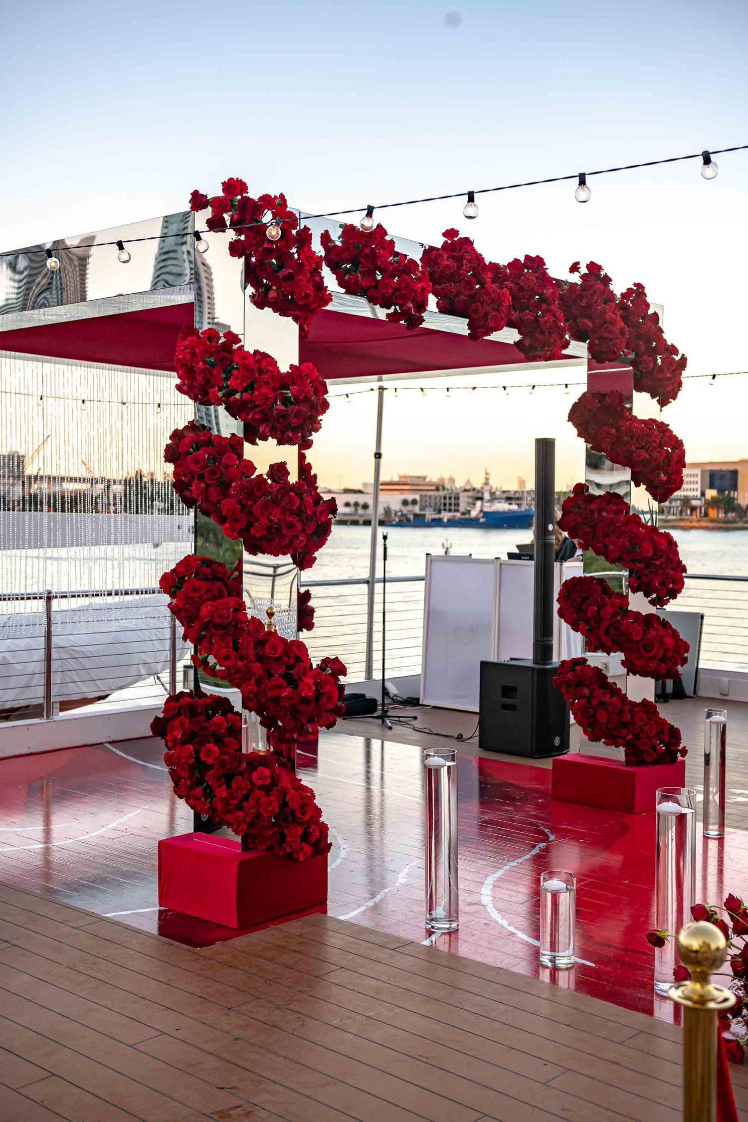 Stunning red rose arch installation on outdoor deck with waterfront views on the Seafair Mega Yacht in Miami.