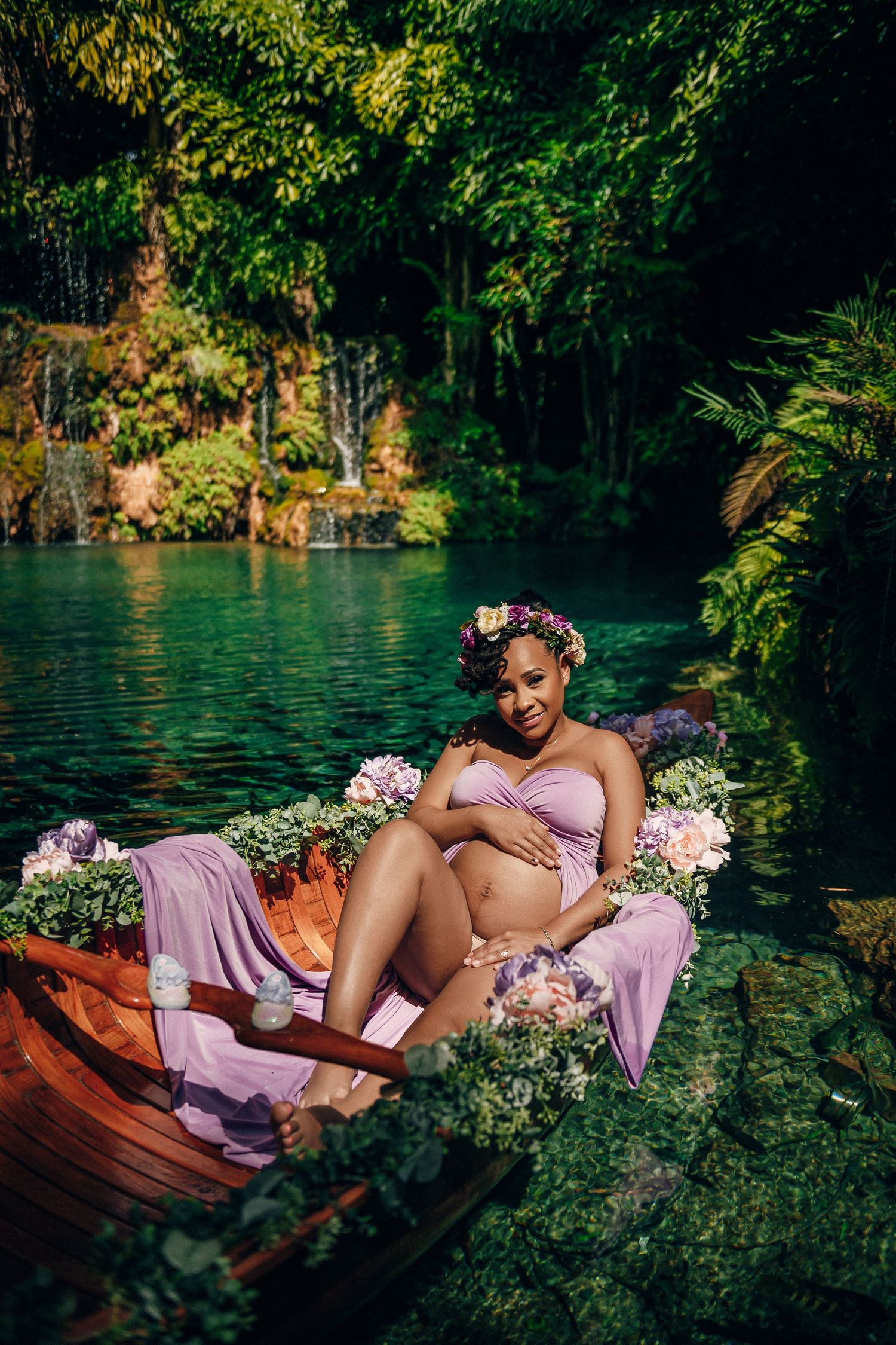 Maternity photo shoot by a serene lake with flowers and lavender fabric.