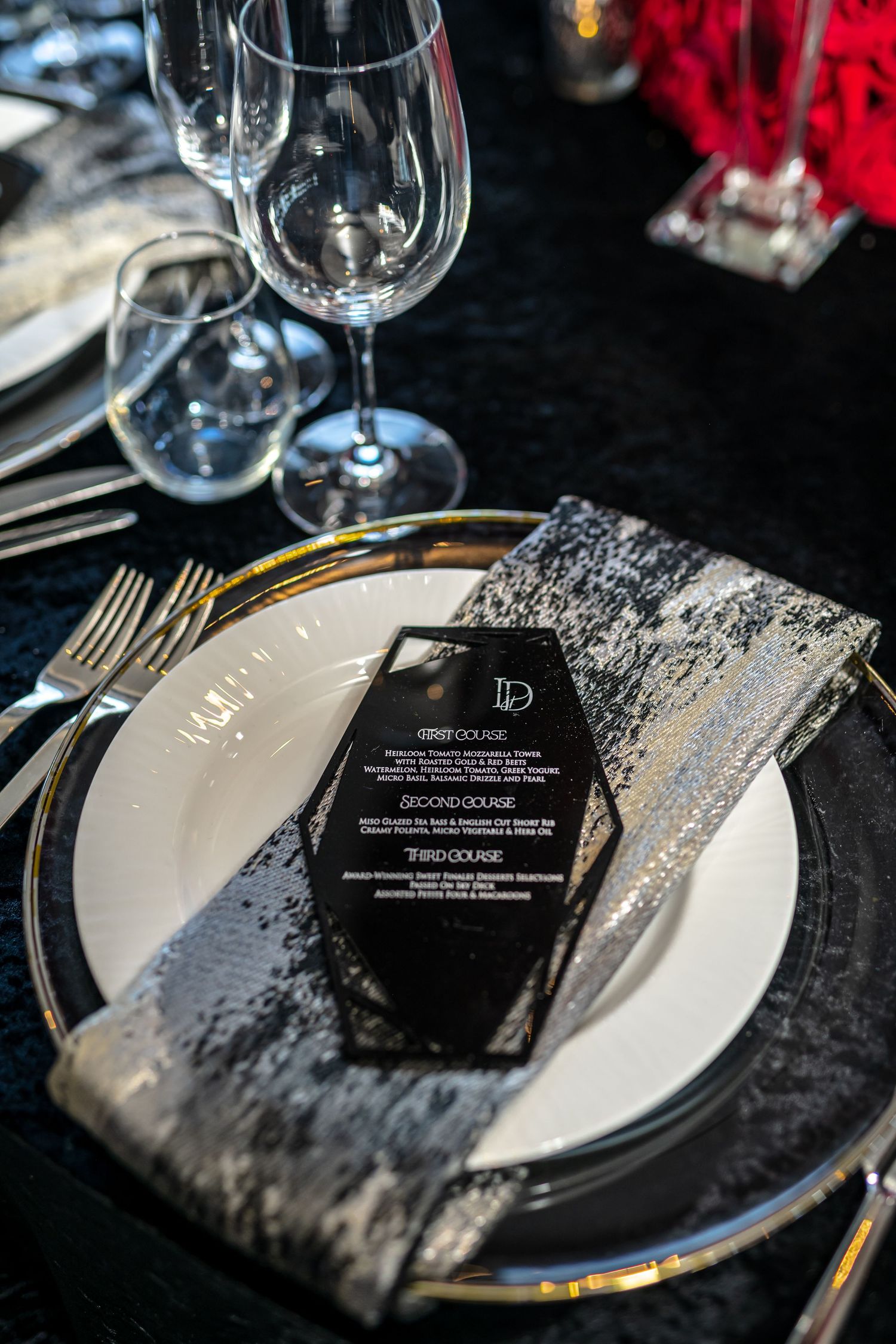 Elegant place settings with black and silver sequined decor on white plates create a luxurious dining atmosphere.