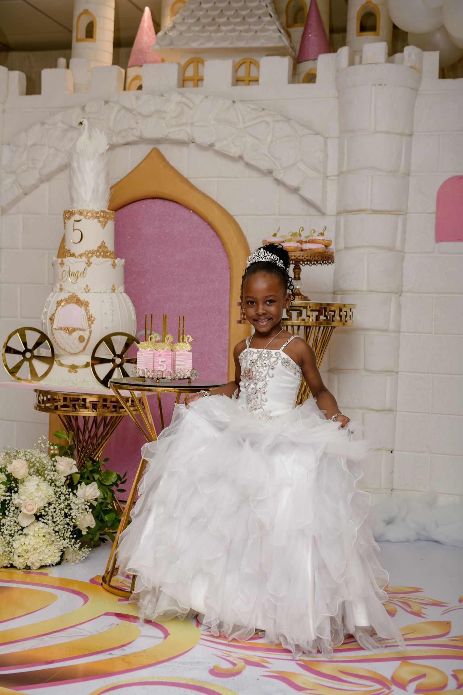 Elegant party setup with white decorative castle backdrop and gold accents for a special celebration.