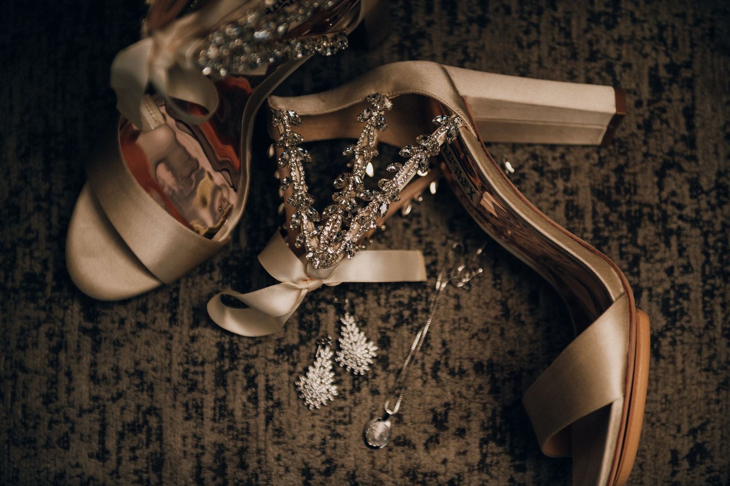 A collection of elegant bridal shoes and accessories arranged artistically on a dark textured background.