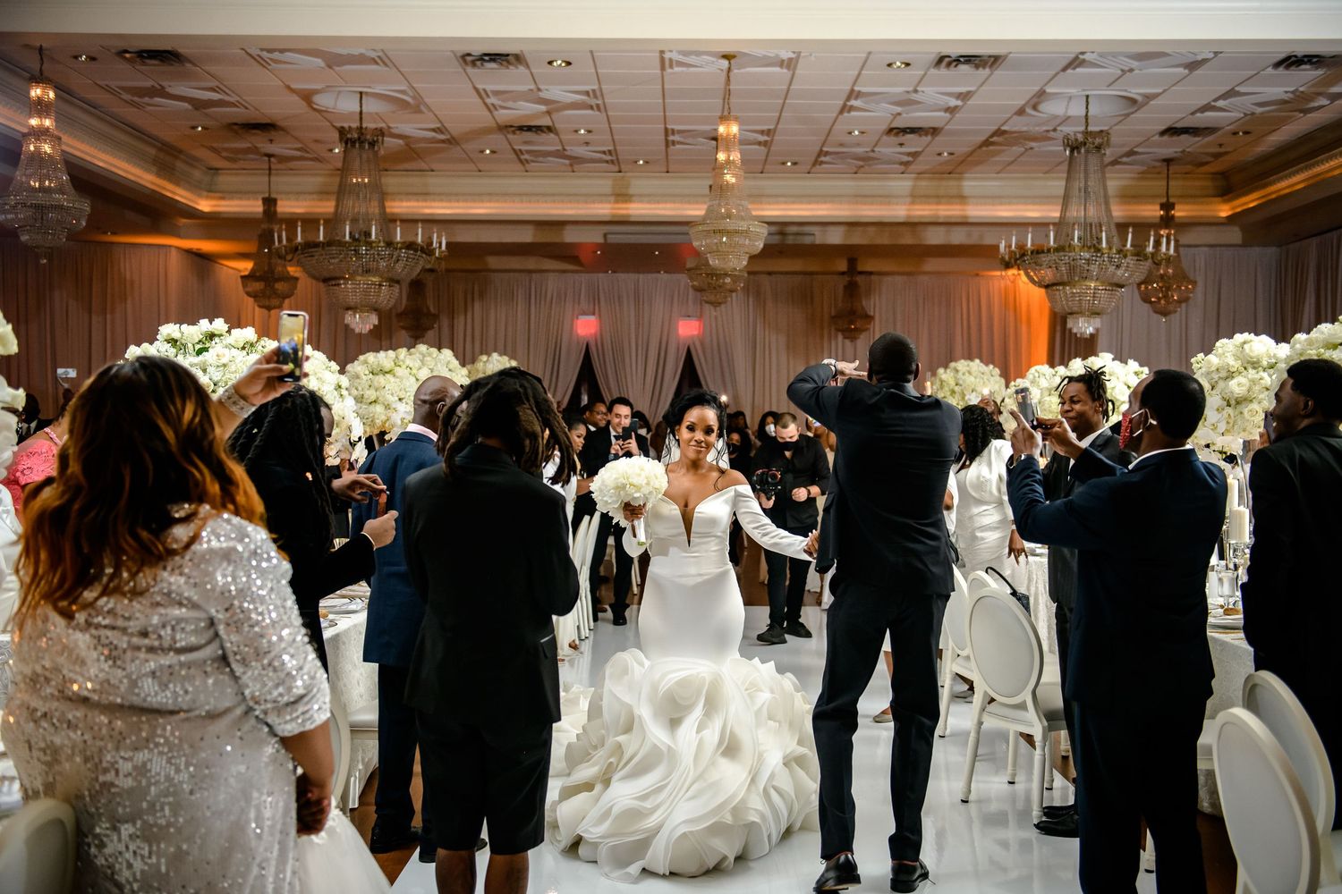 Wedding guests dance together on an elegant ballroom floor during a reception celebration.