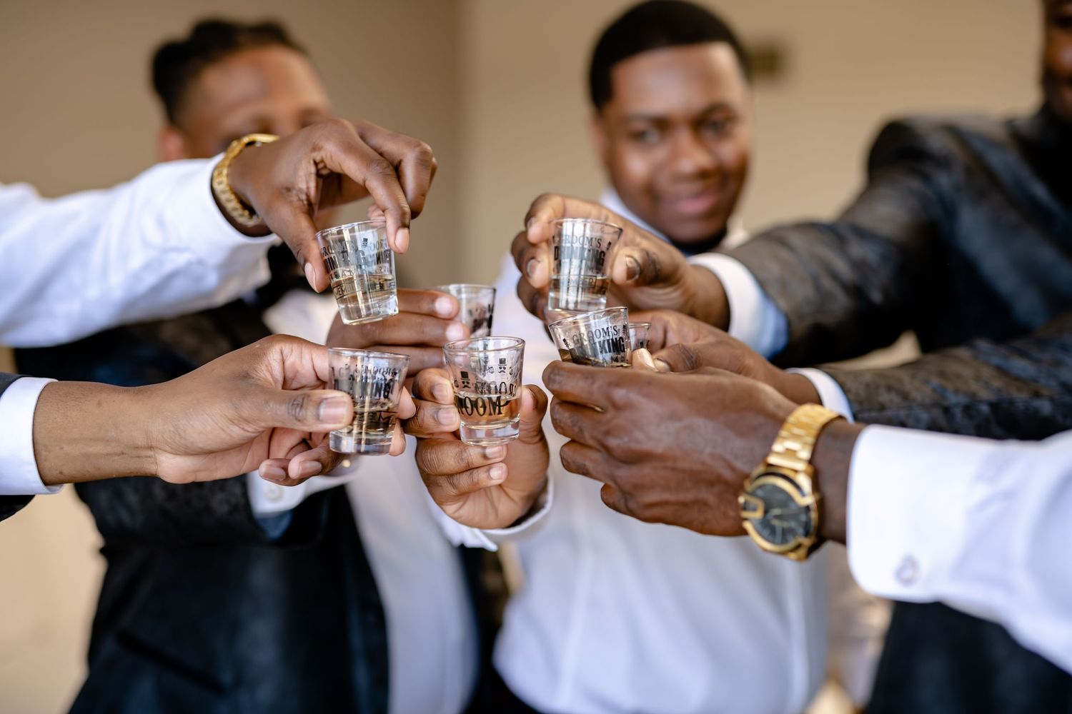 Multiple hands clink shot glasses together in a celebratory toast sequence.