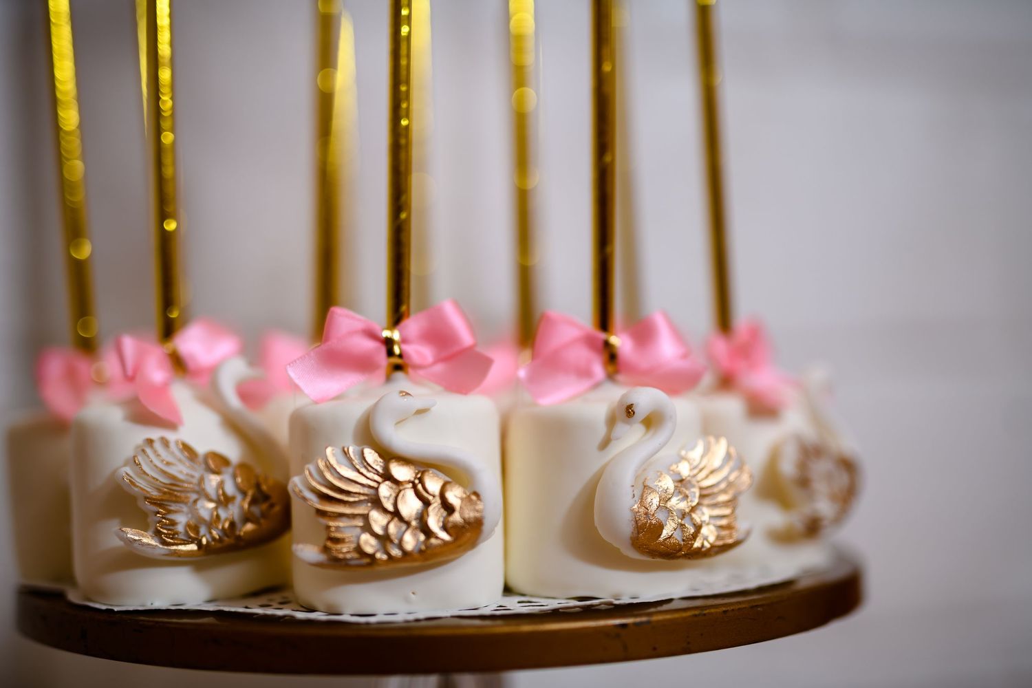 Pink and gold decorated desserts and treats arranged on wooden serving platters with tall gold candles.