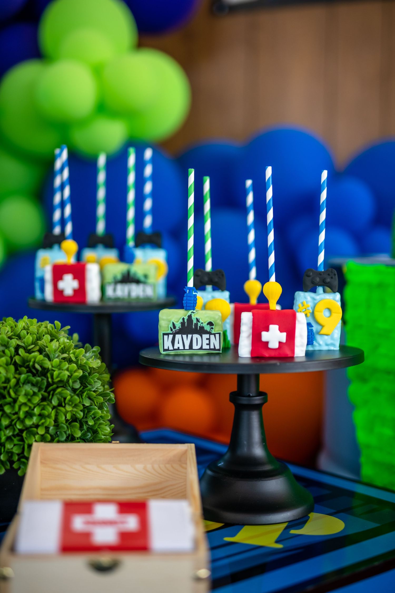 Gaming themed party decorations with blue and green balloons, candles, and party favors arranged on a table.