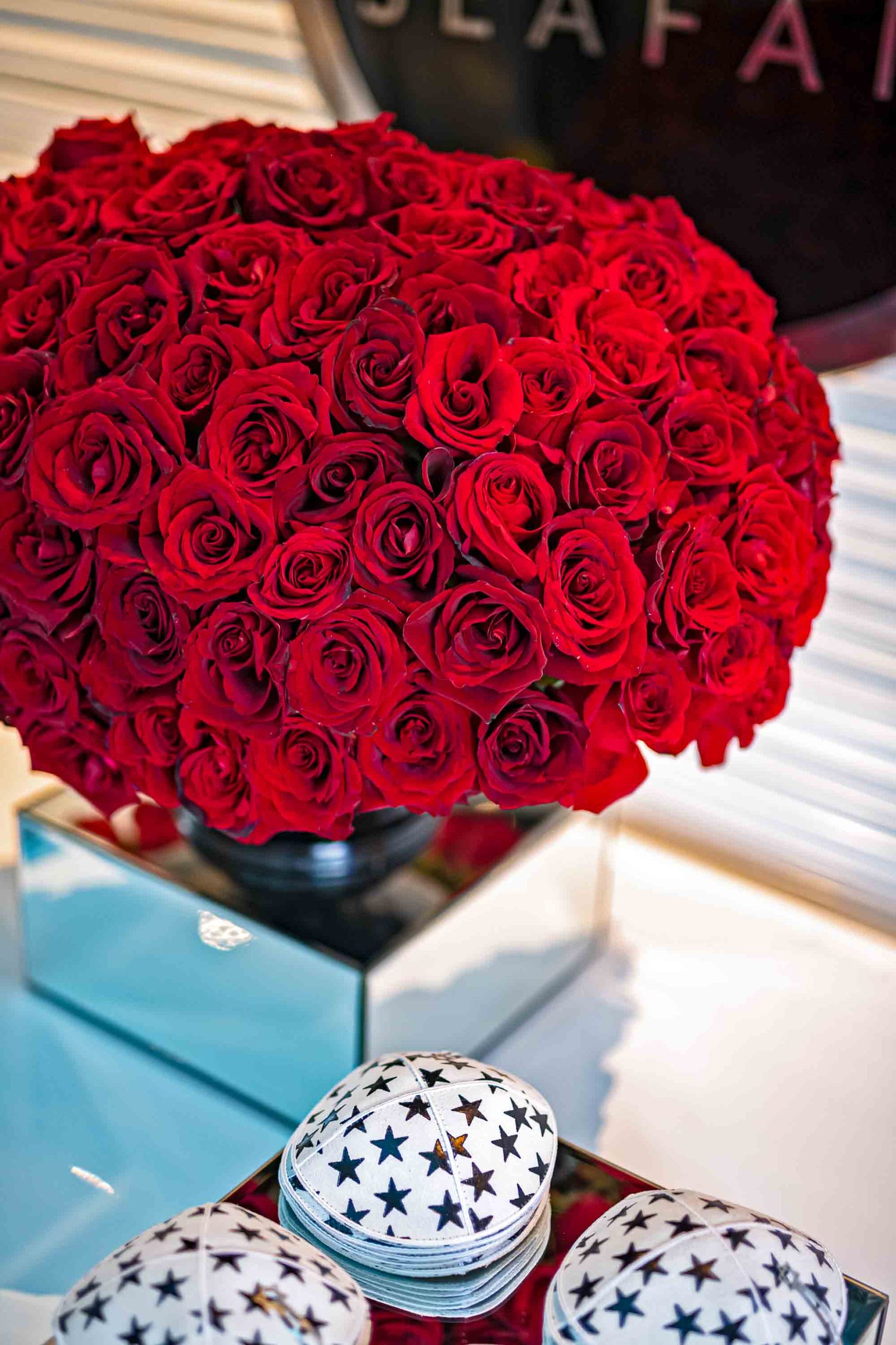 Stunning spherical arrangement of deep red roses displayed above decorative star-patterned boxes on the Seafair Mega Yacht in Miami.