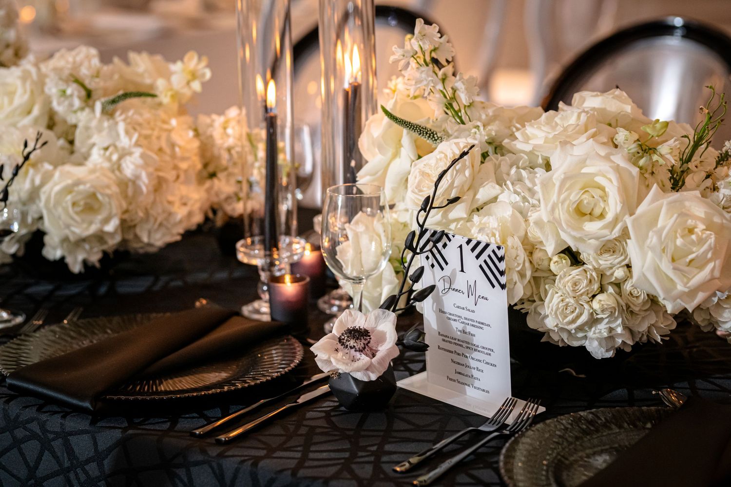 Elegant wedding reception table settings with white roses, candles, and crystal glassware create a romantic atmosphere.