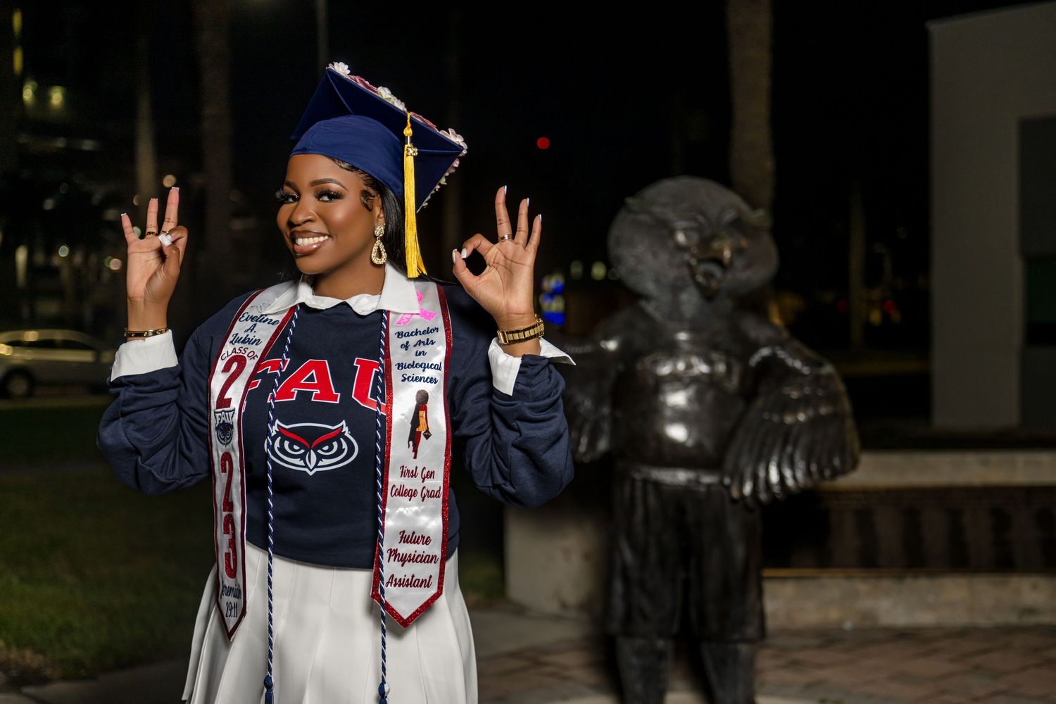 Graduates in caps and gowns celebrate with peace signs and smiles during commencement ceremony.