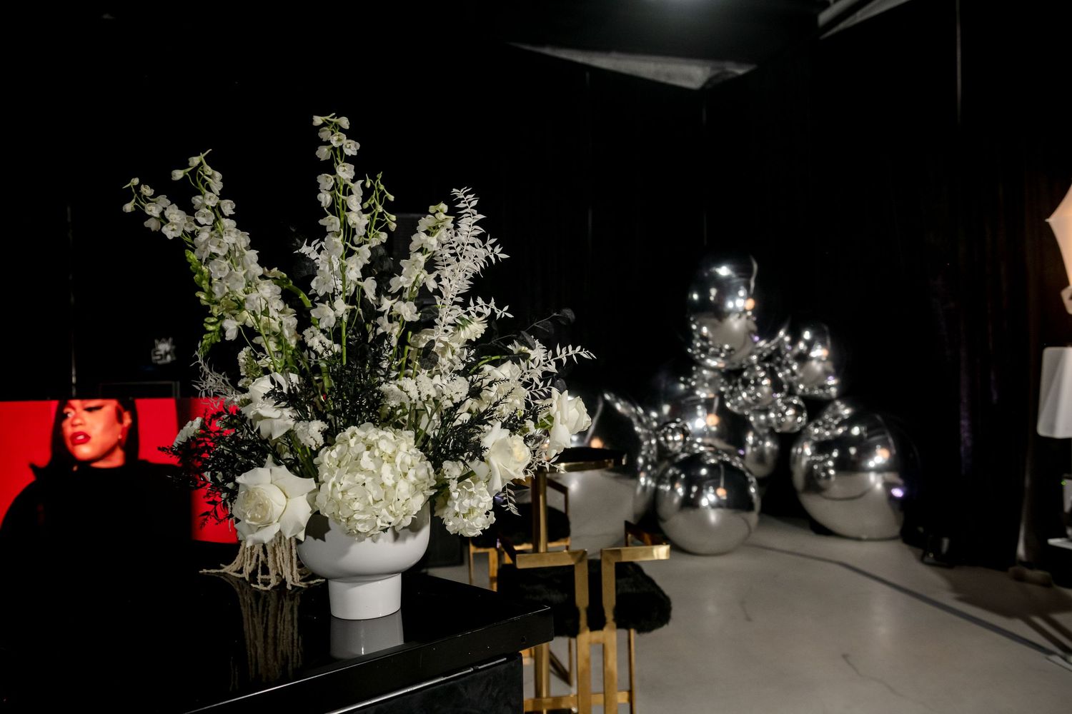 White floral arrangements in glass vases create an elegant display against a dark backdrop.