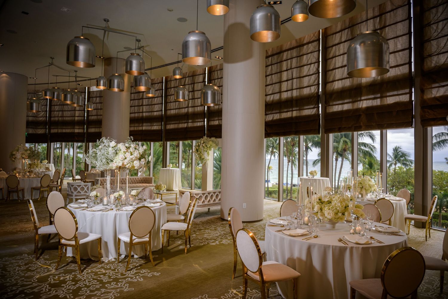 Elegant wedding reception venue with round tables, white linens, and warm lighting in a modern restaurant setting.
