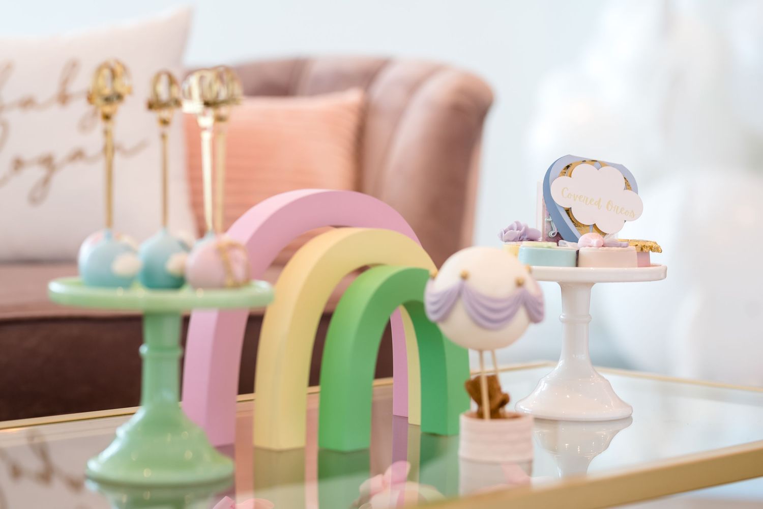 Pastel colored macarons and desserts displayed in a delicate pink and mint green themed bakery setting.