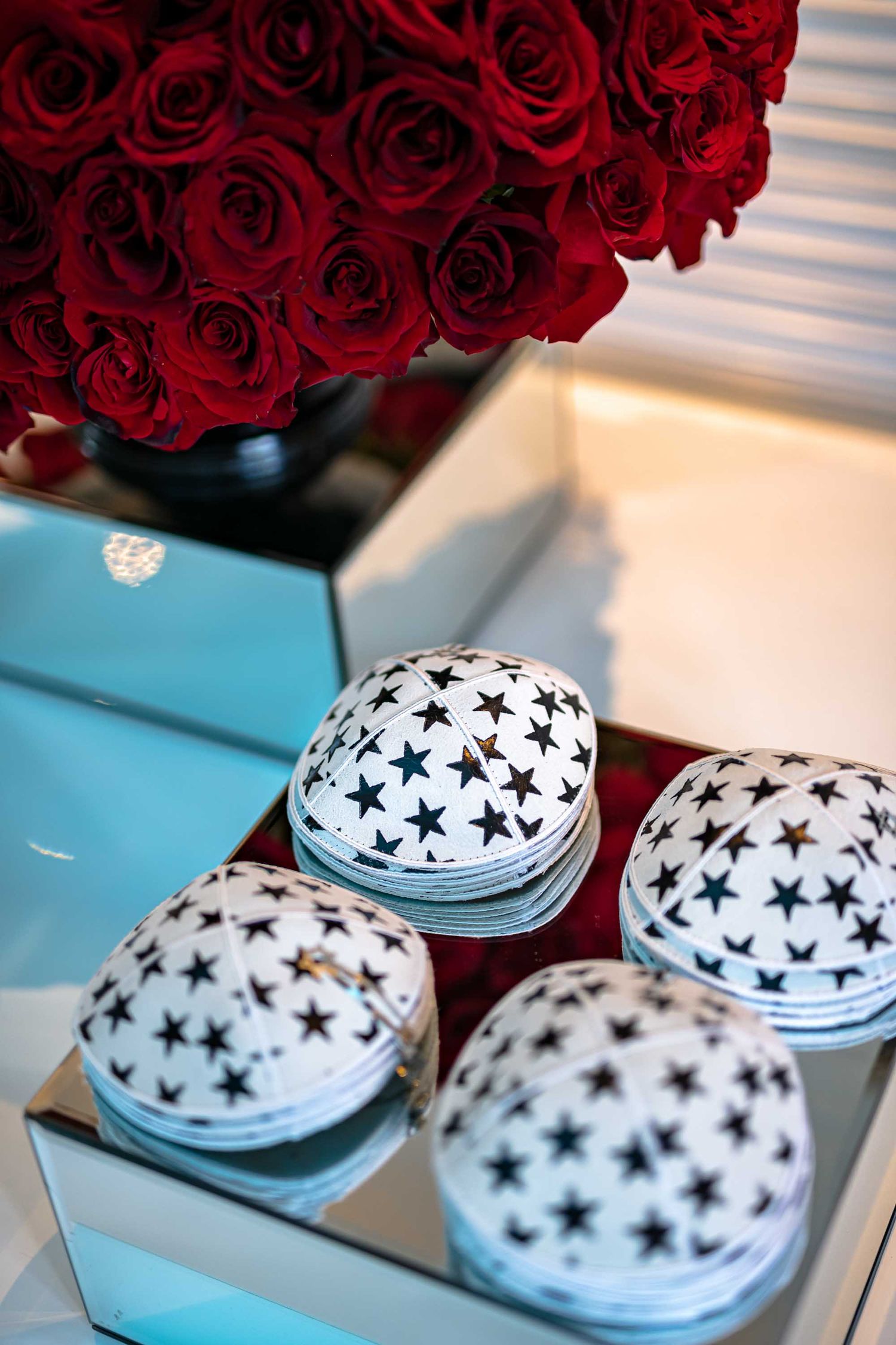Close-up of star-patterned decorative boxes beneath a lush arrangement of red roses on the Seafair Mega Yacht in Miami.
