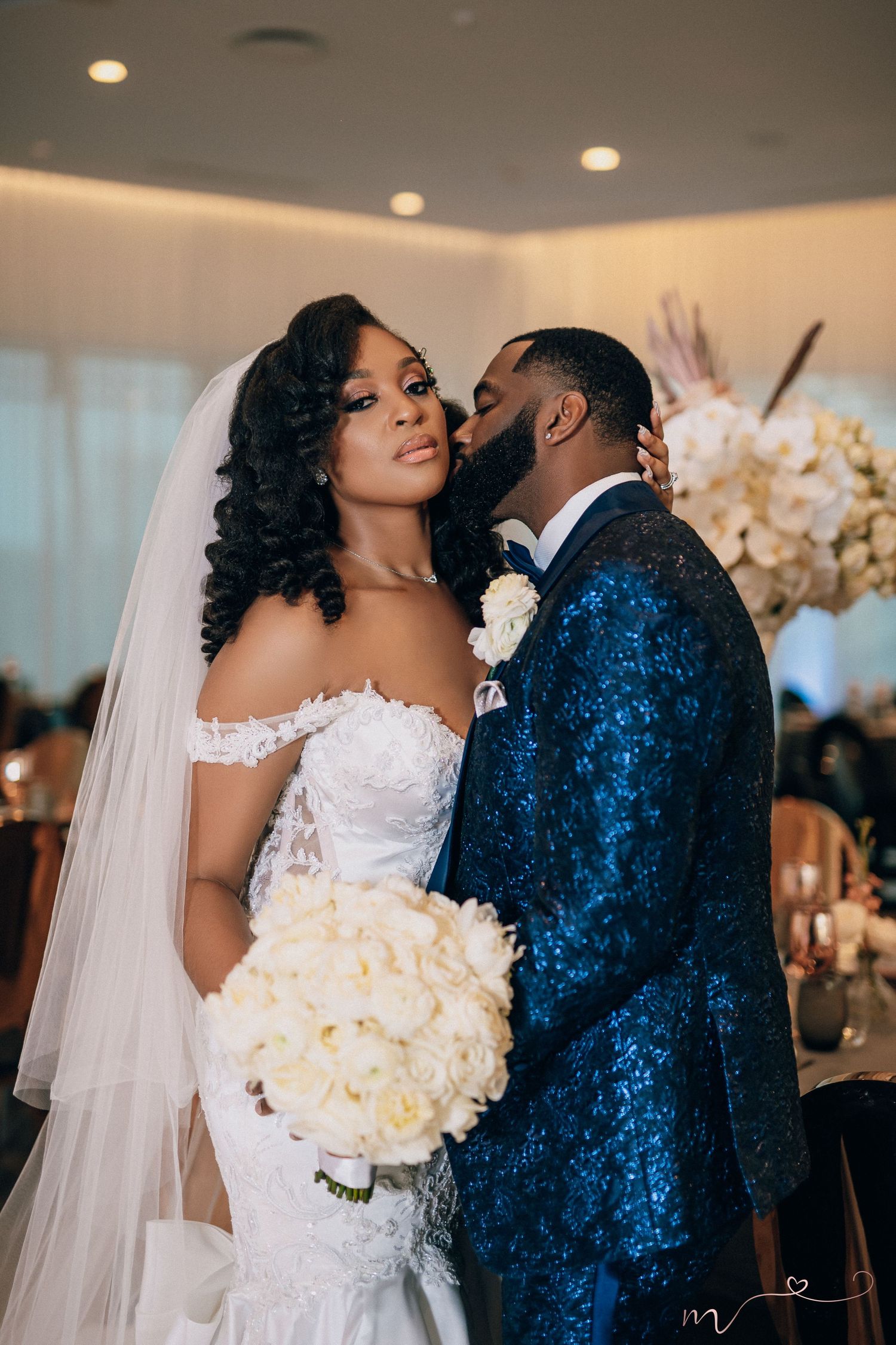 A tender wedding scene with the bride in white and groom in blue velvet sharing sweet moments.