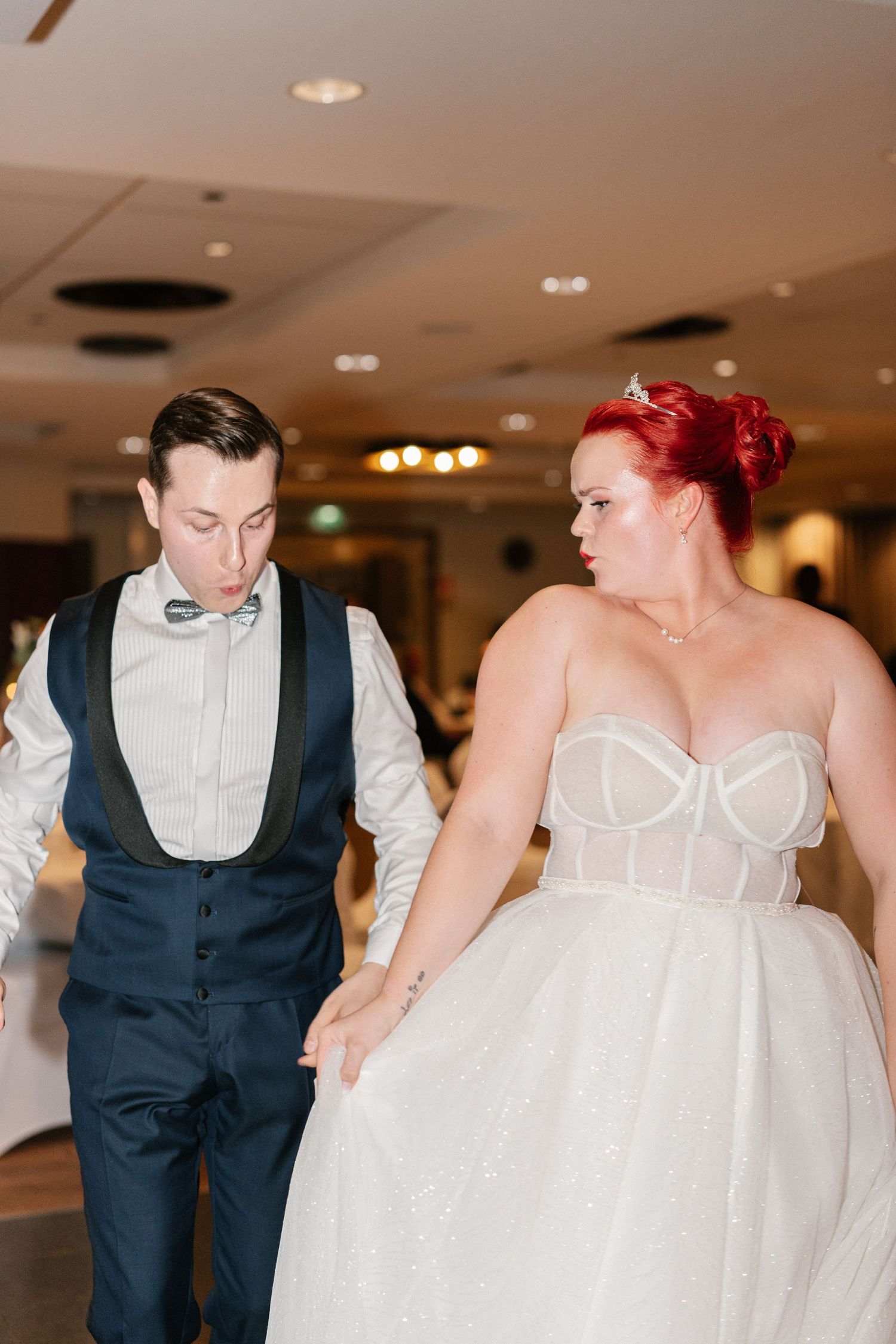 A couple dances together at their wedding reception in formal attire.
