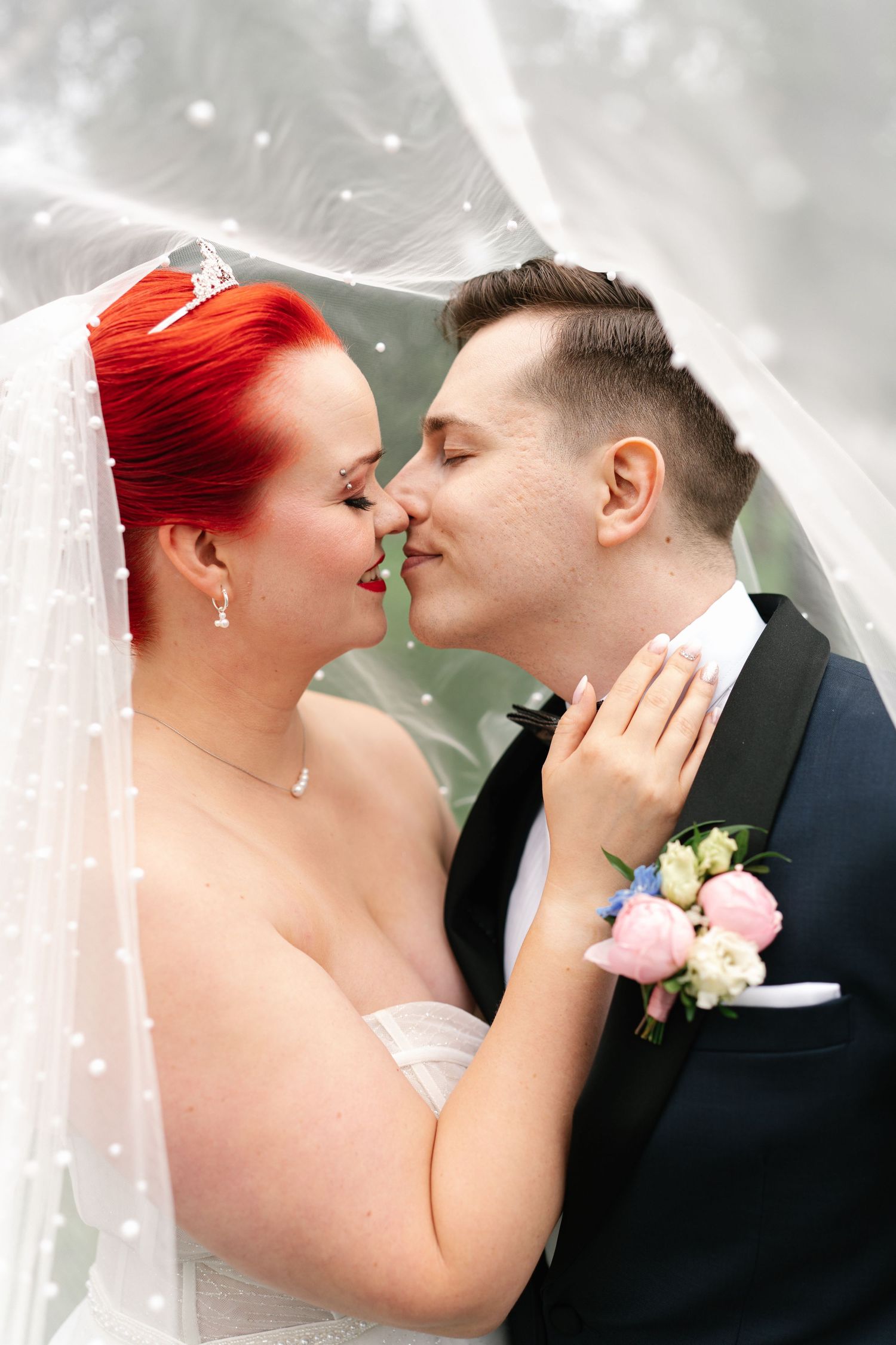 Ethereal close-up of wedding couple sharing tender moment with flowing veil.