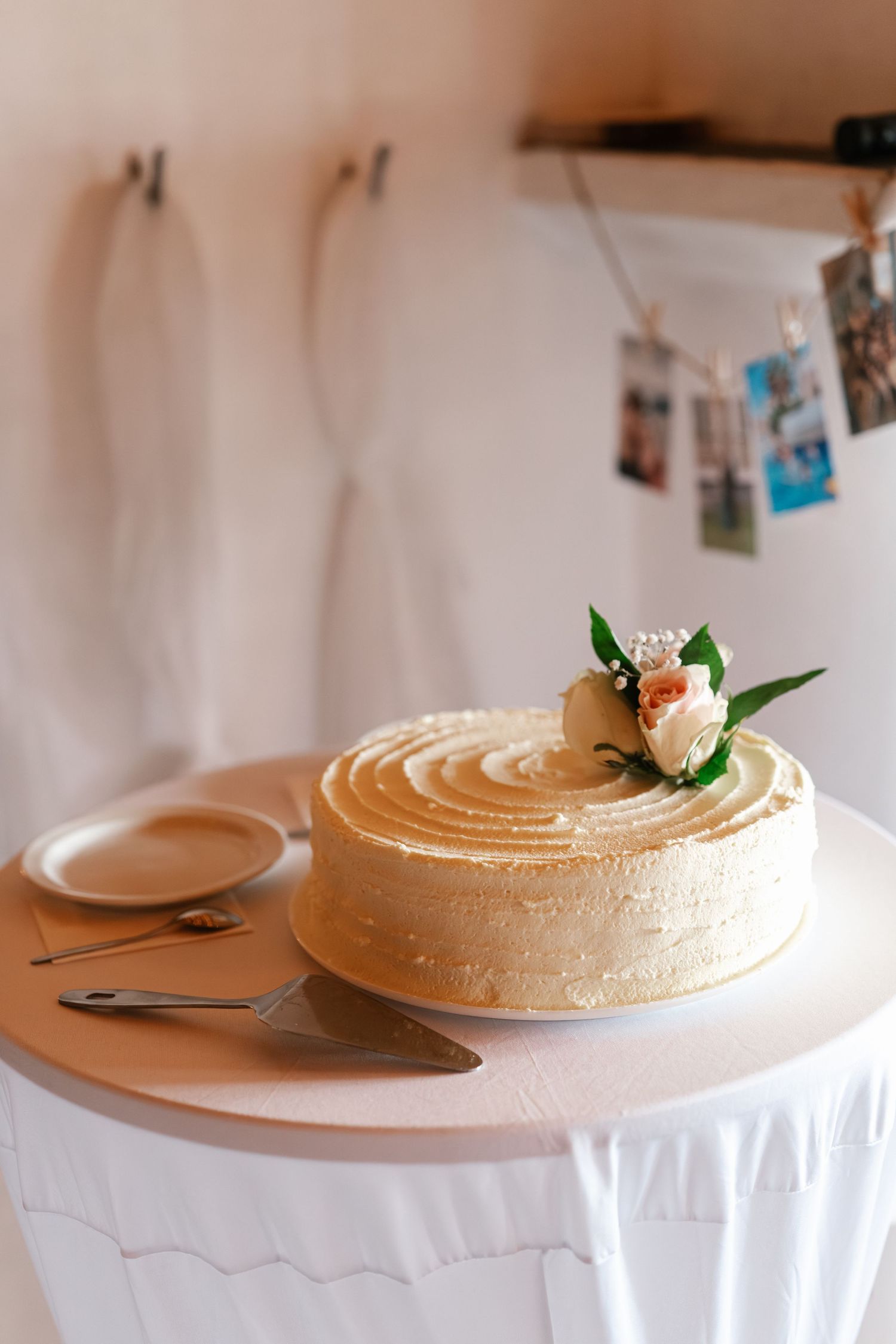 Elegant wedding cake with buttercream frosting decorated with a fresh flower on a white tablecloth.