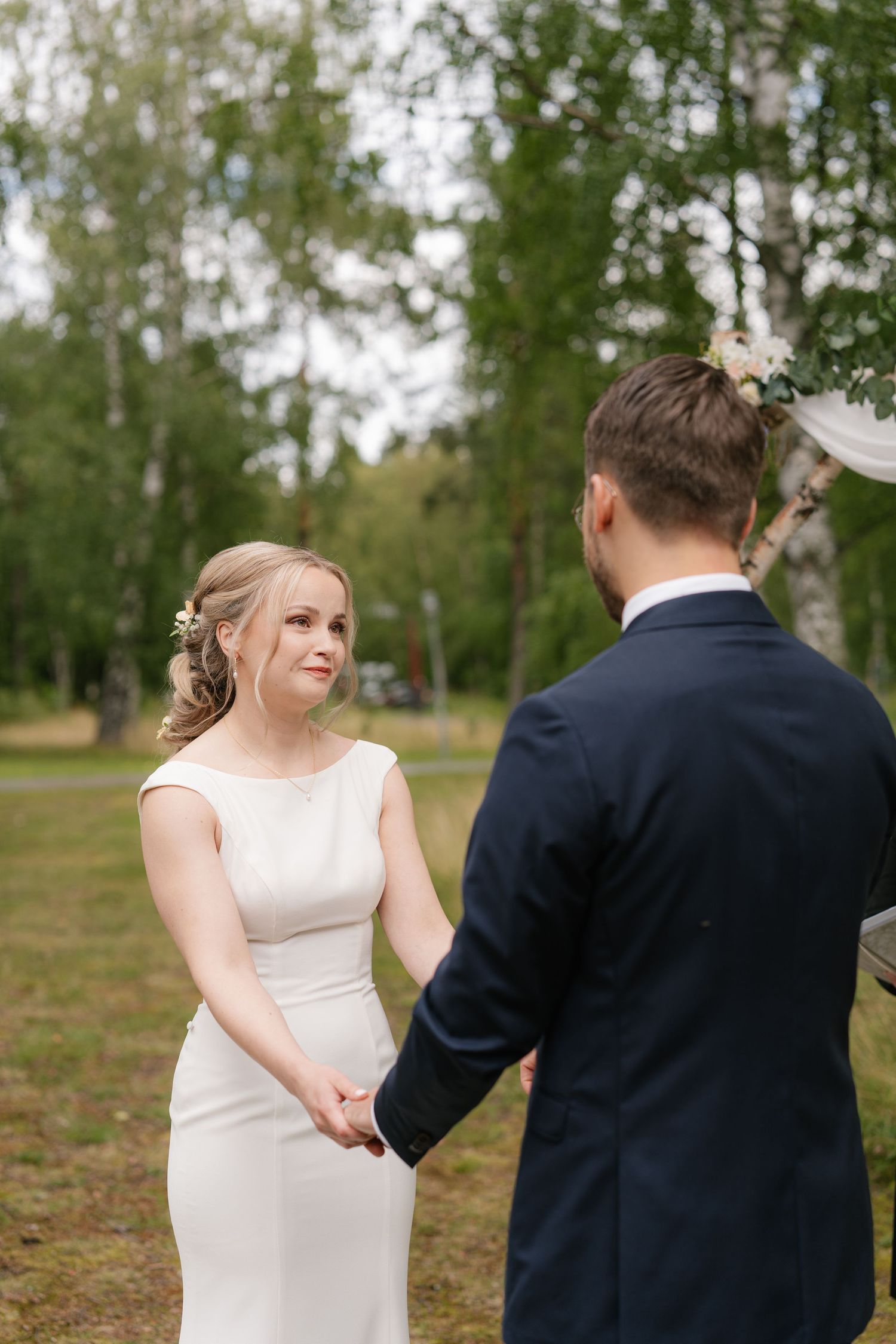 Close-up shots of a wedding ceremony with bride in white dress and groom in navy suit exchanging rings.