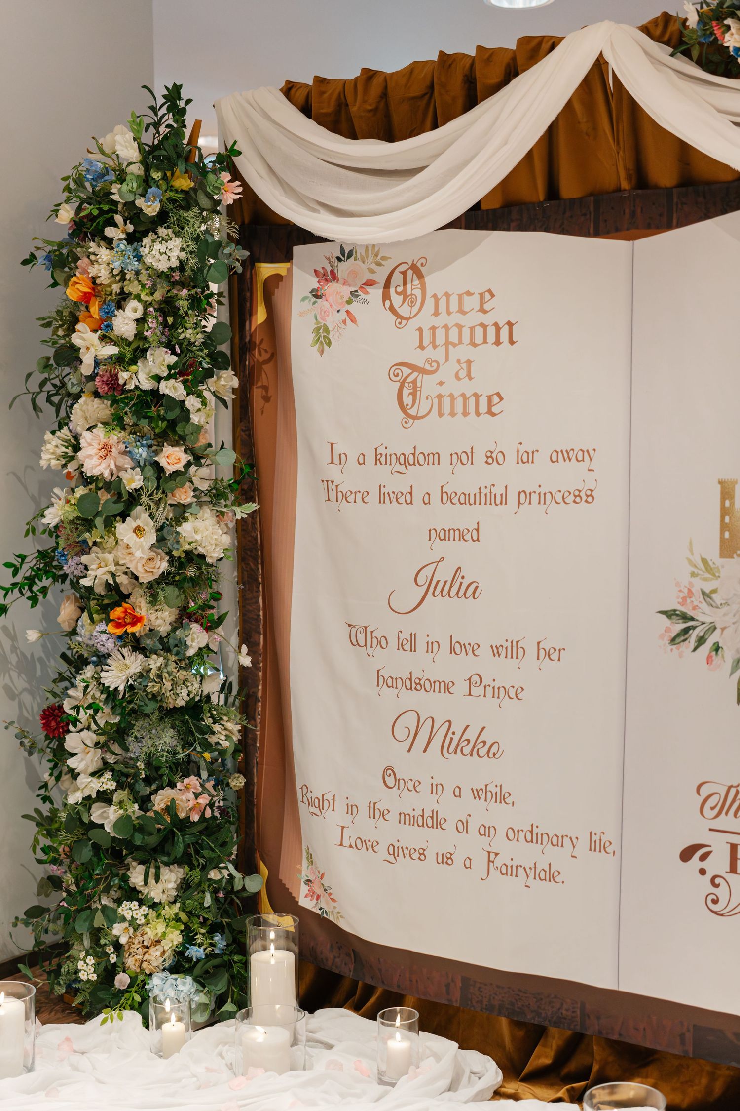 Decorative wedding backdrop with fairytale story text and floral arrangements.