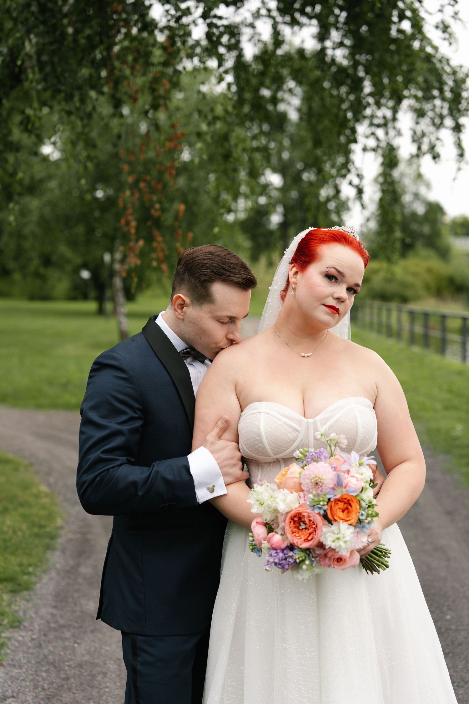 Romantic outdoor wedding photos on a path with bride holding peach and pink bouquet.