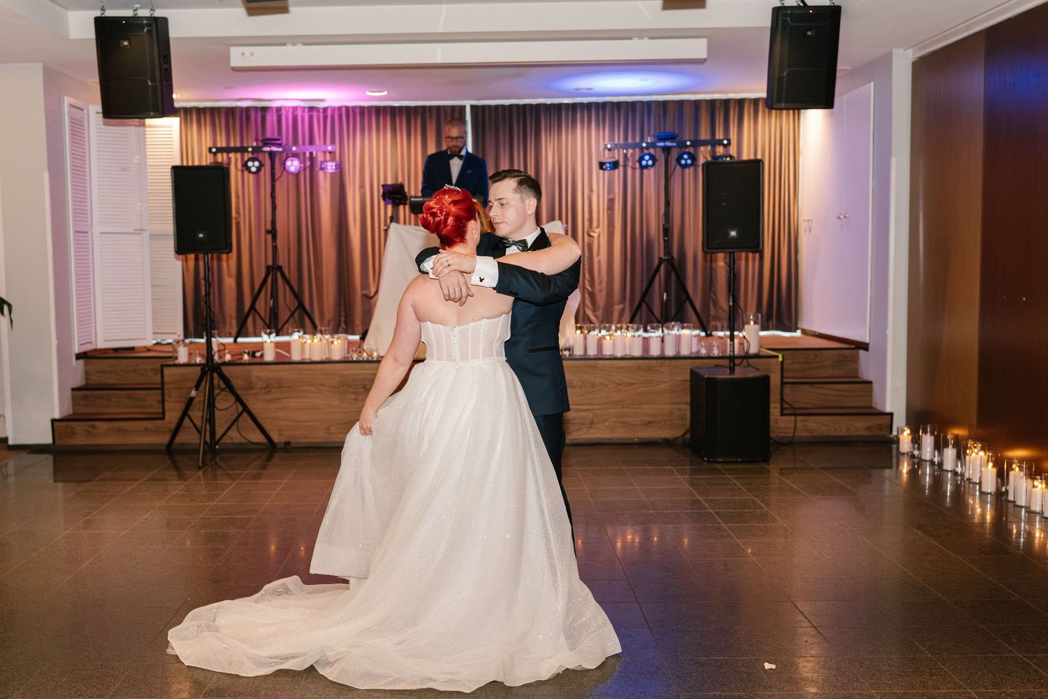 Wedding reception dance floor scene with purple lighting and white decorative details.