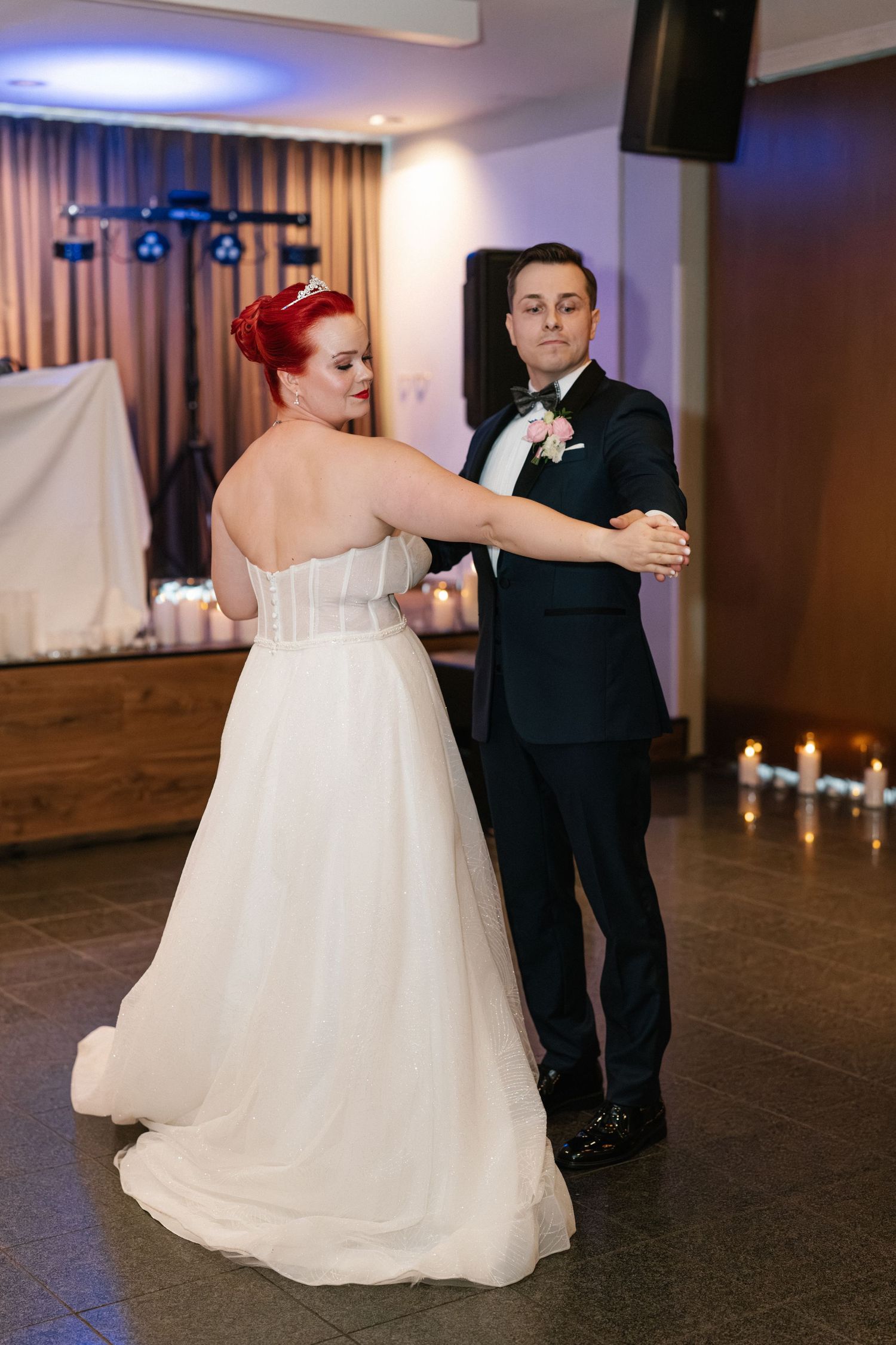 Couple sharing their first dance together at an elegantly lit wedding reception venue.